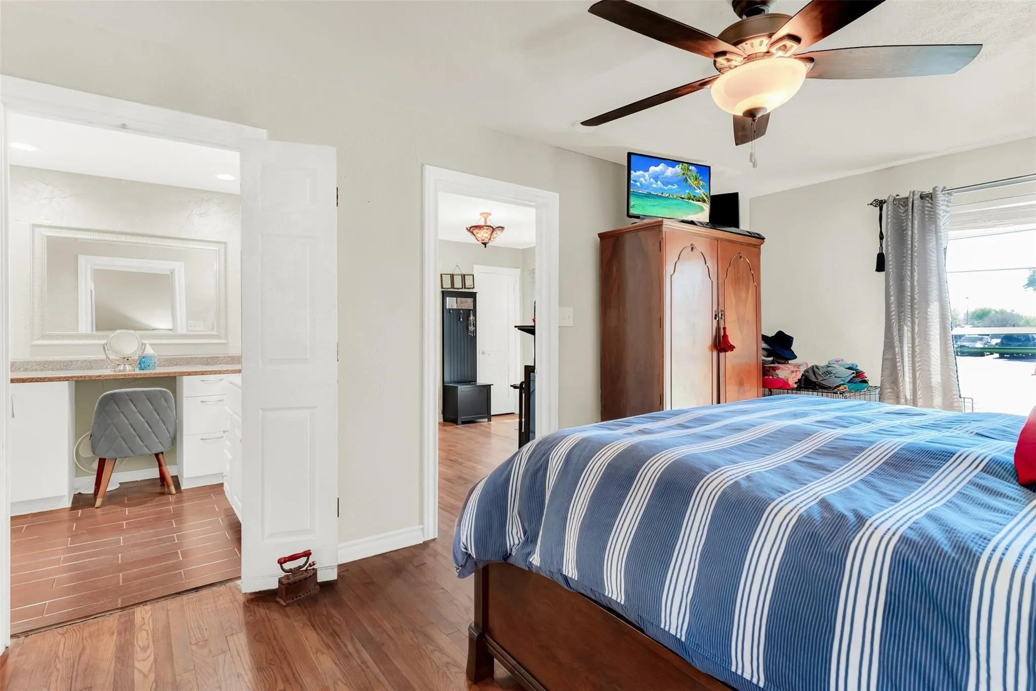 Hardwood-finish flooring throughout, ceiling fan with integrated lighting, and a built-in vanity with countertop and mirror