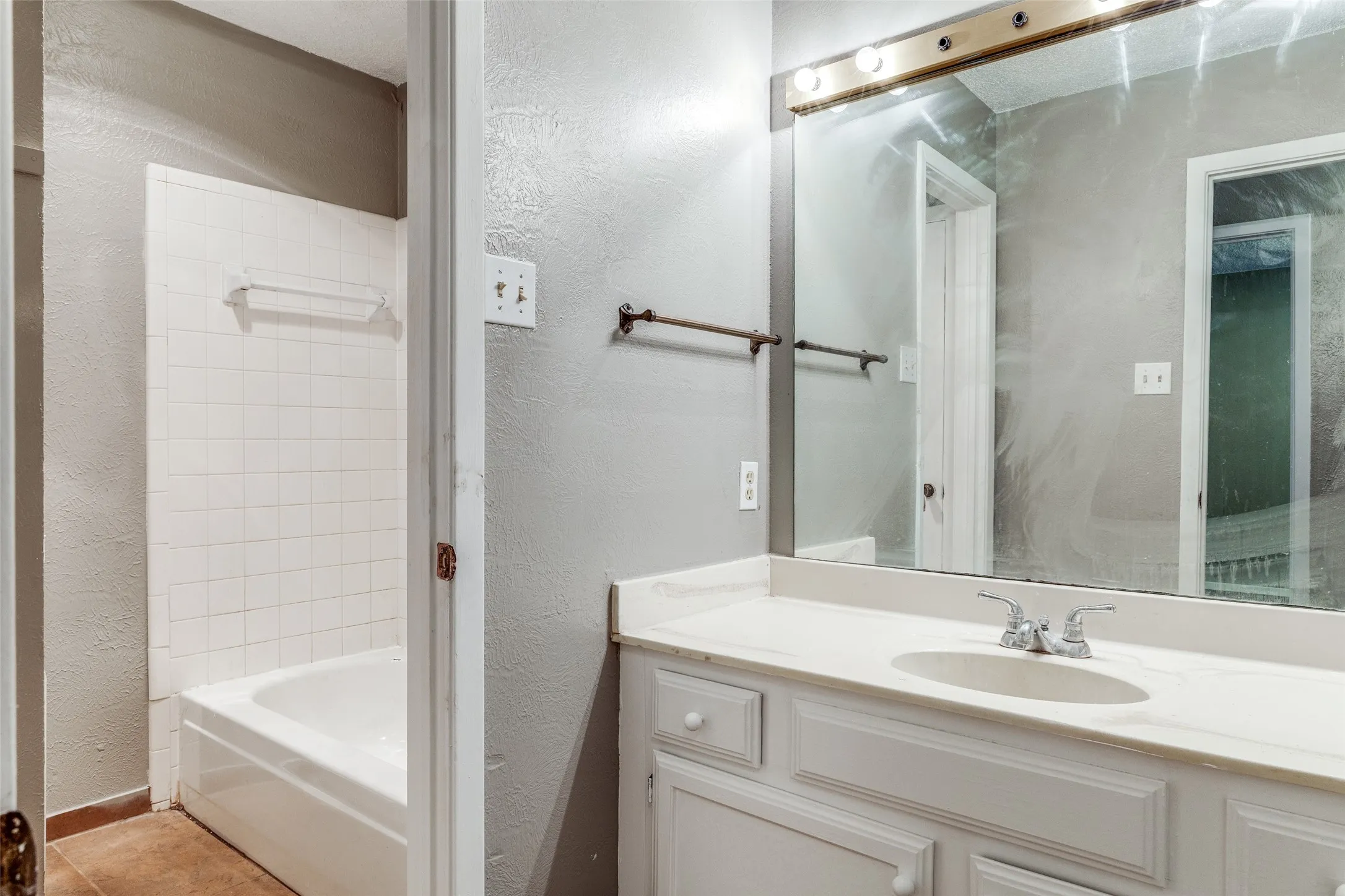 White tile shower surround, integrated bathtub, and vanity with built-in sink