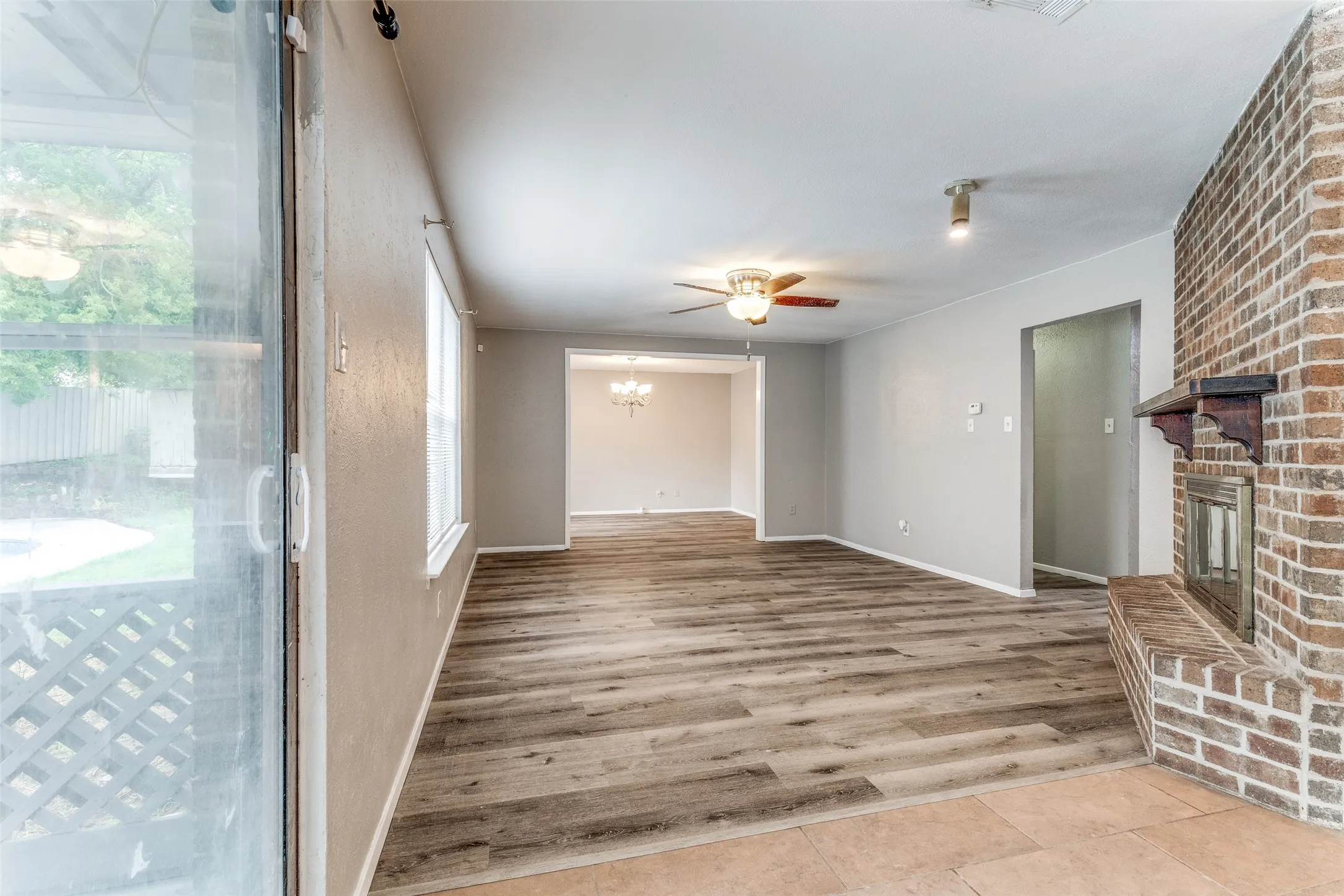 Brick fireplace, wood-finish flooring, ceiling fan, sliding glass door, and recessed lighting