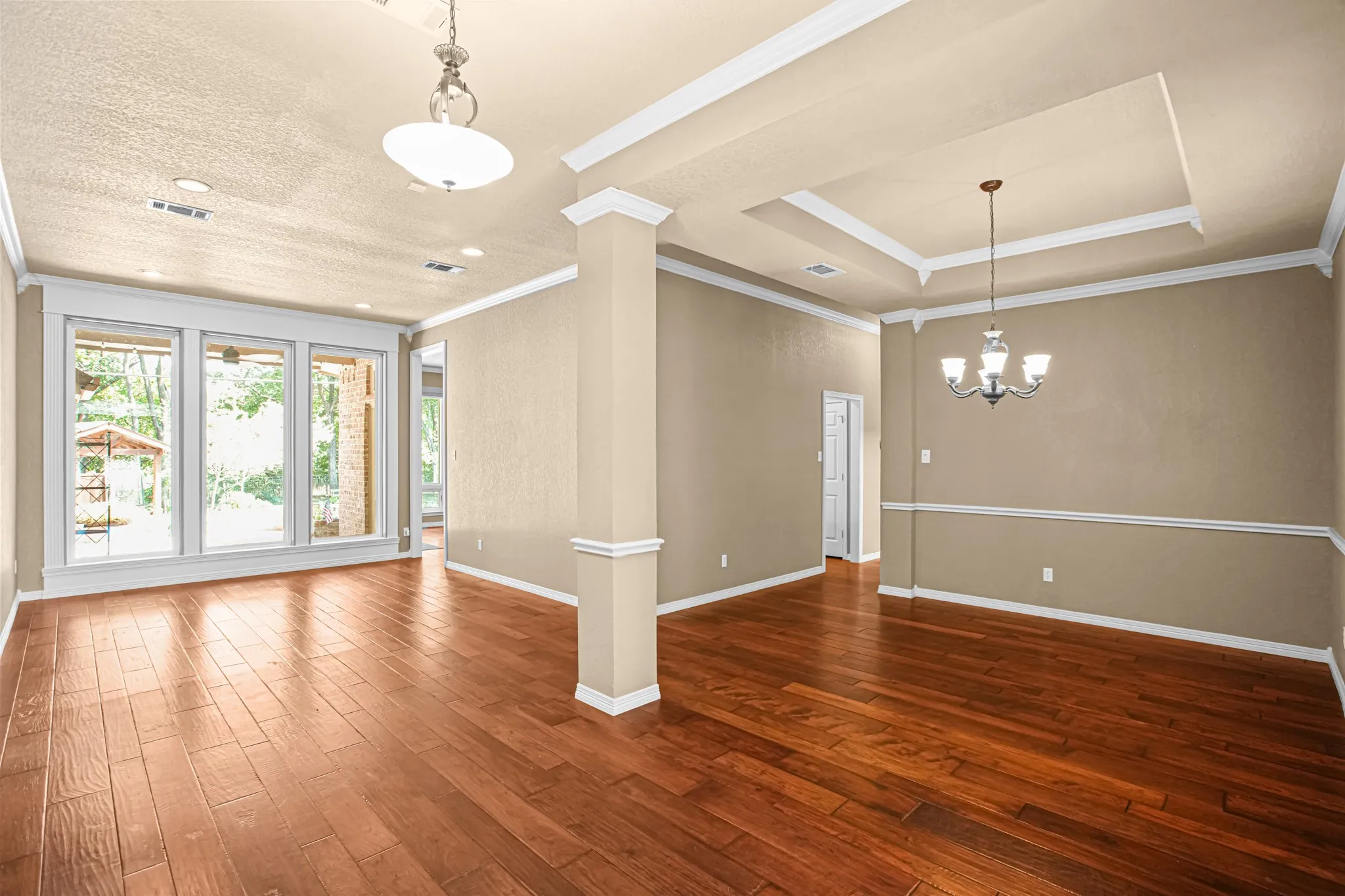 Wood-finish flooring throughout, featuring a tray ceiling, recessed lighting, and a decorative chandelier