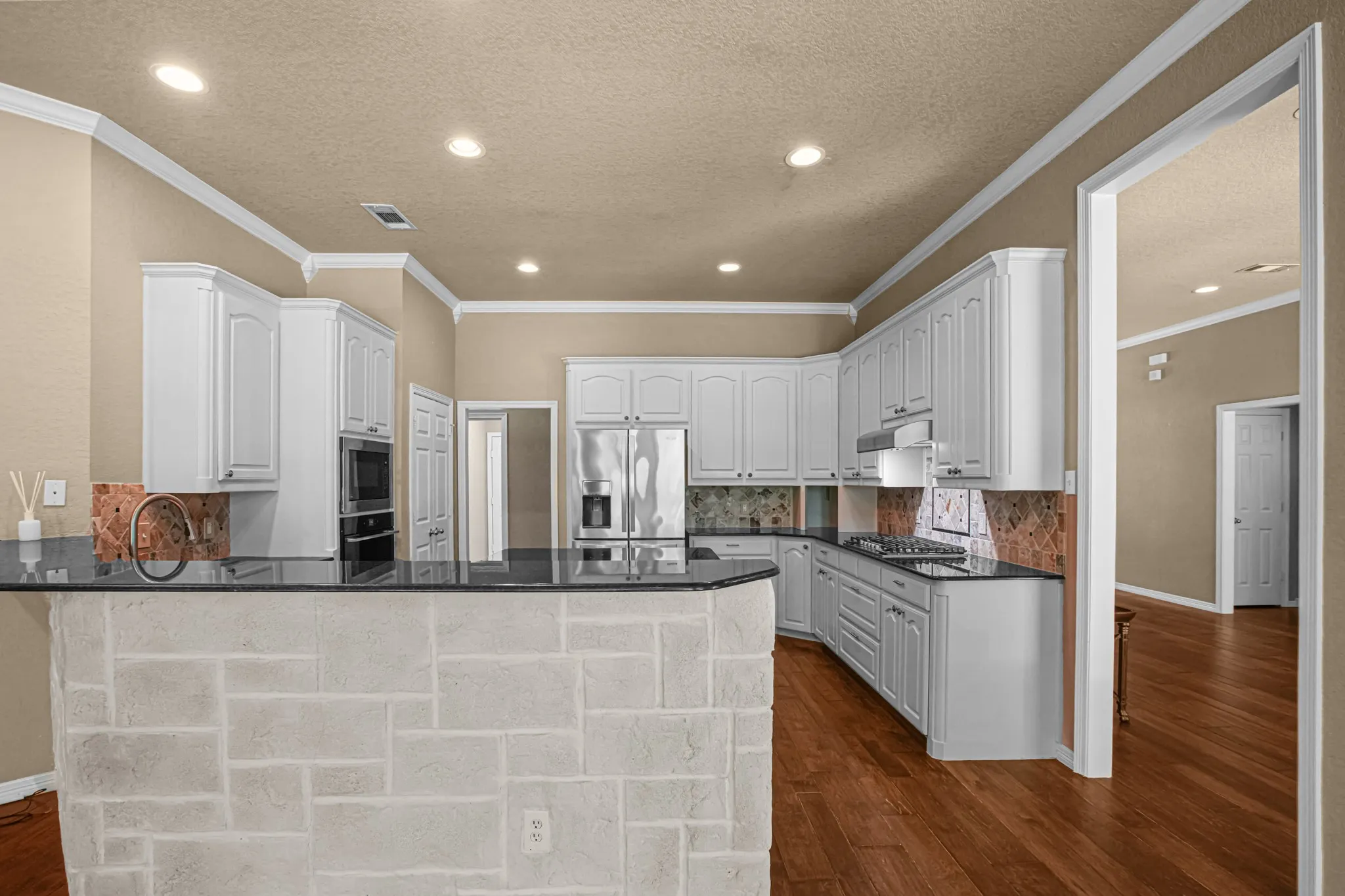 Kitchen featuring white cabinetry, dark countertops, built-in double oven, stainless steel appliances, and wood-finish flooring