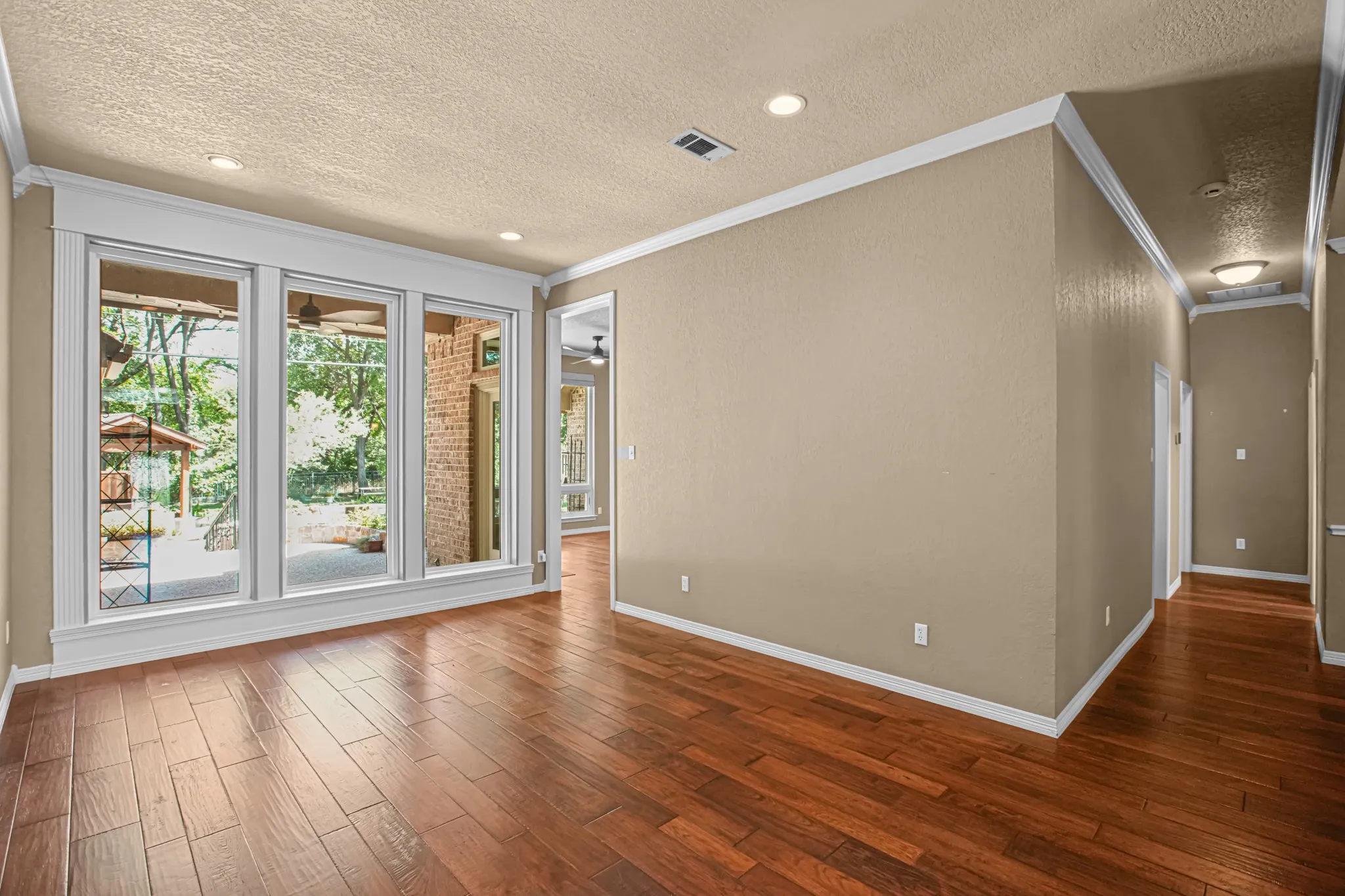 Wood-finish flooring, recessed lighting, crown molding, and expansive windows