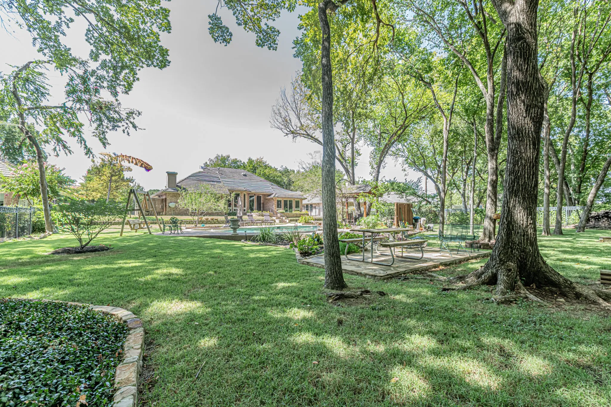 Expansive backyard with a manicured lawn, established trees, and a defined patio area