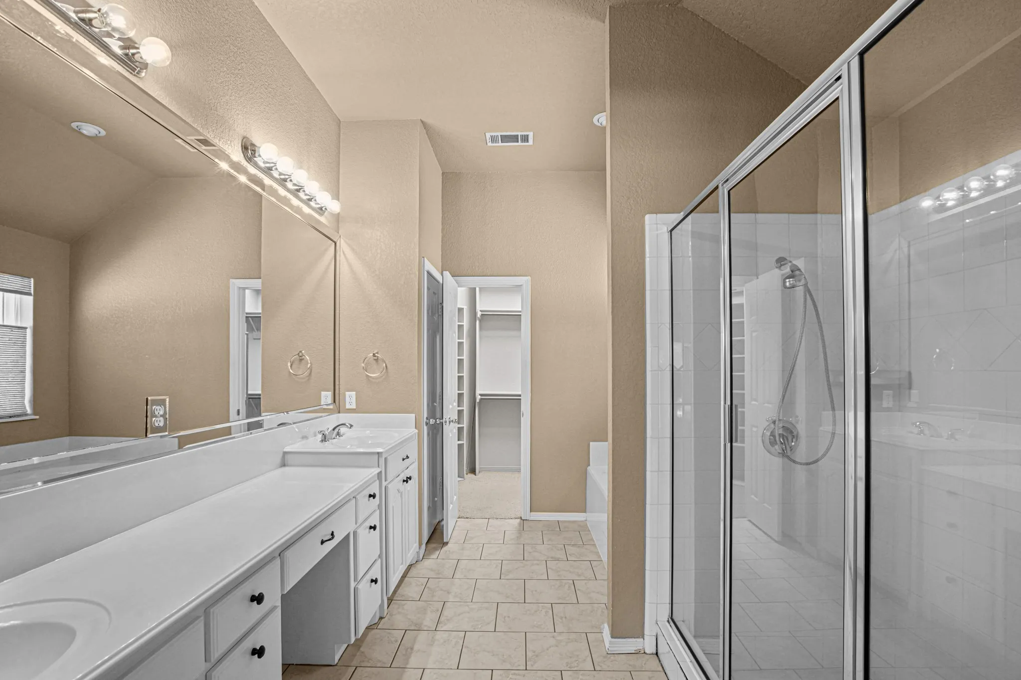 Dual vanity with integrated sinks, frameless glass shower enclosure, separate soaking tub, and tile flooring