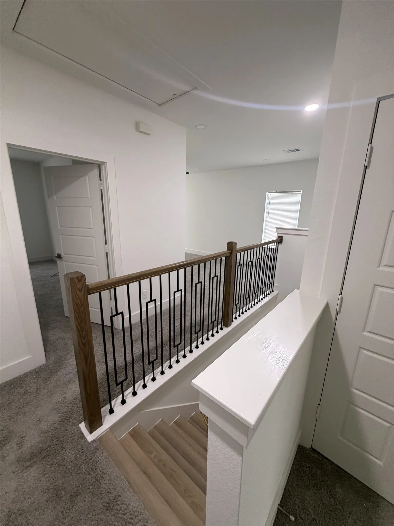 Modern stair railing with wood-finish handrail and black metal balusters