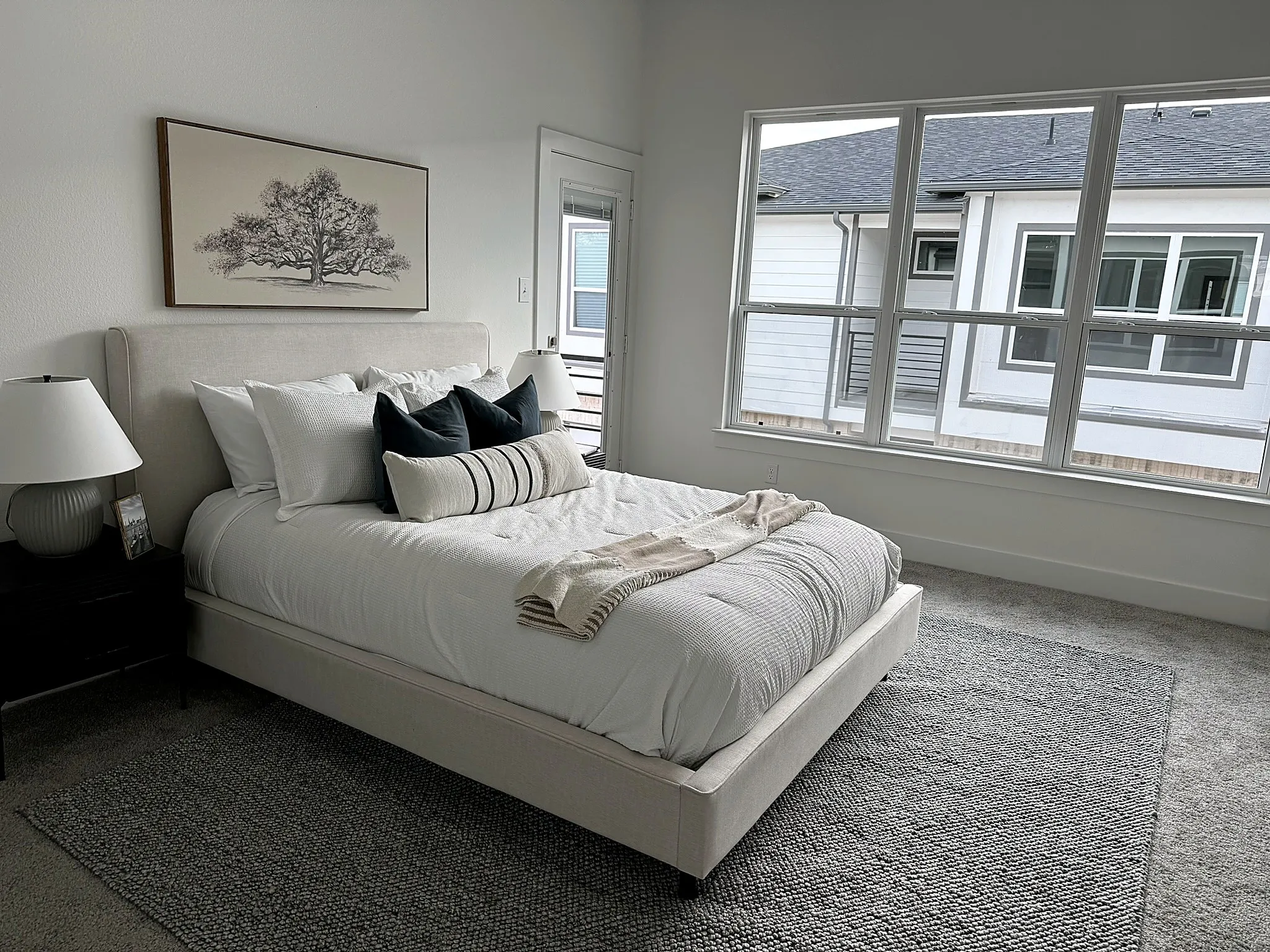 Expansive multi-pane window, neutral carpet flooring, white painted walls, and a private exterior door