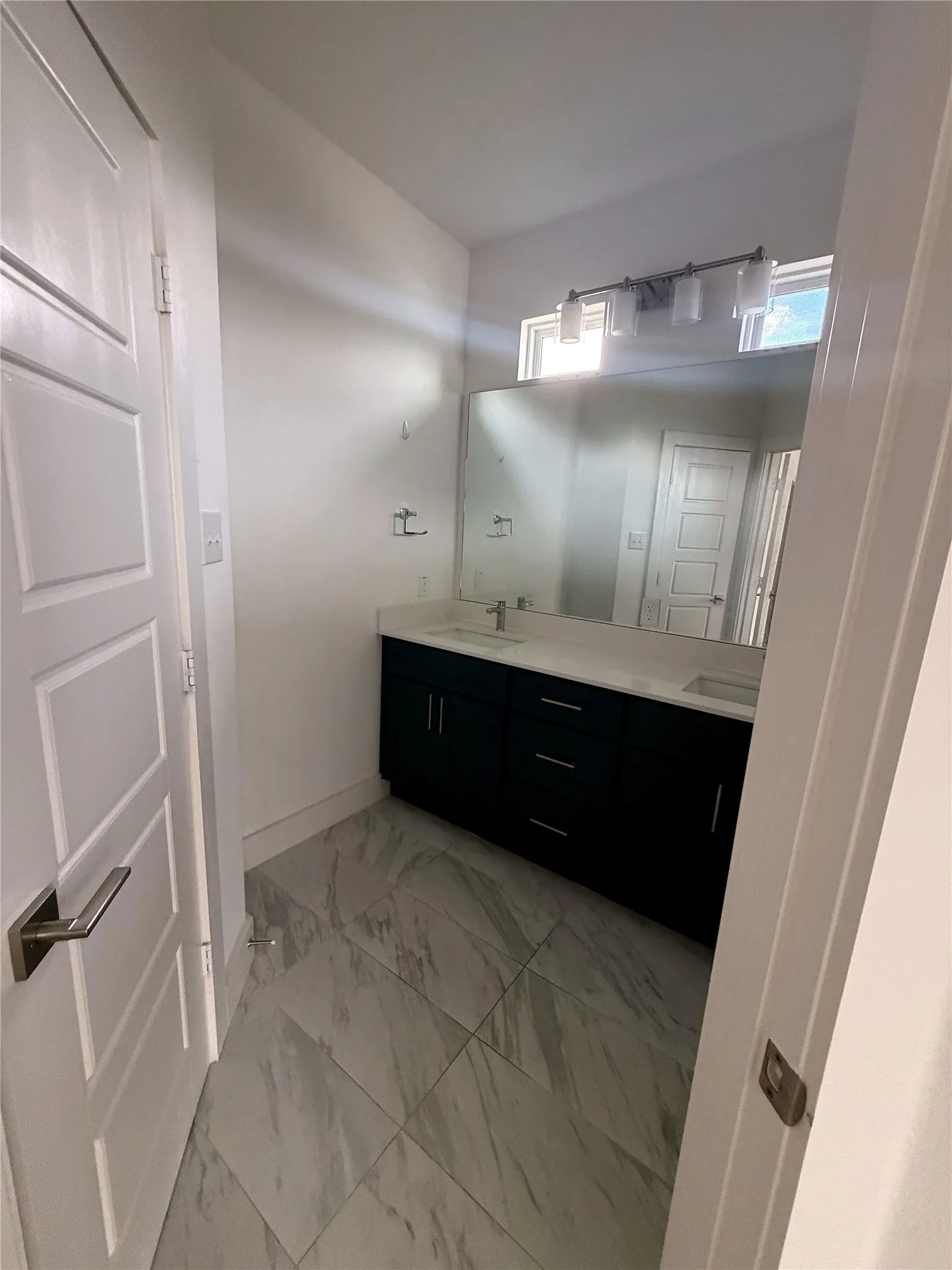 Dual vanity with dark wood-finish cabinetry and undermount sinks, set beneath a large wall-mounted mirror