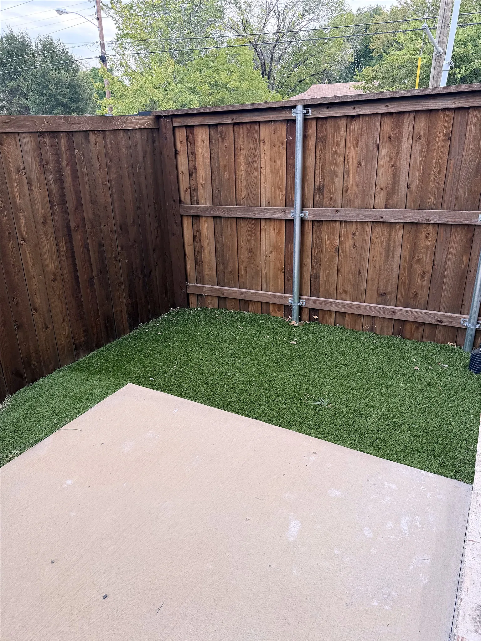 Private outdoor space featuring a composite wood fence, artificial turf, and a concrete patio