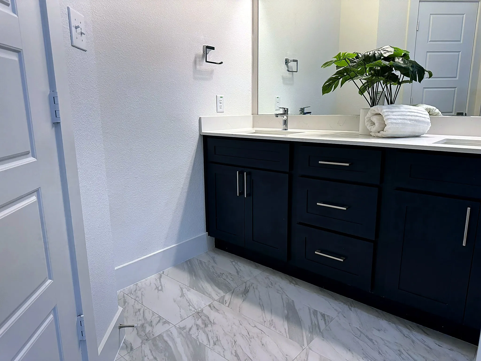 Dual vanity with dark blue cabinetry, white countertop, and modern silver hardware