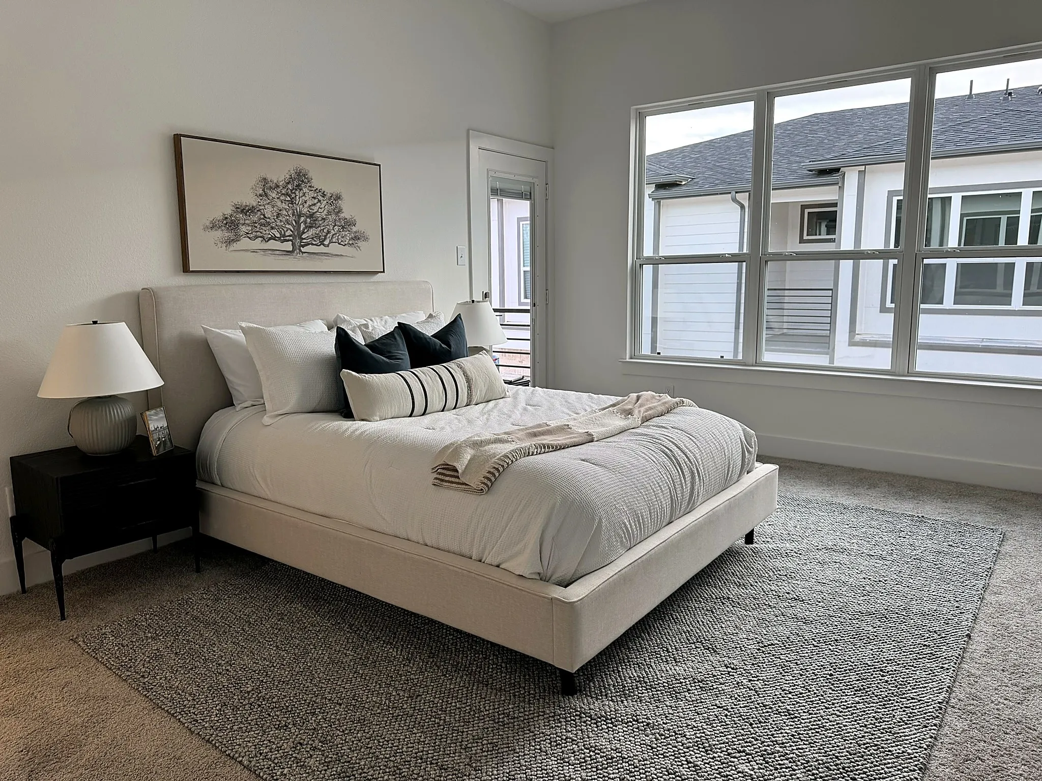 Spacious room featuring broad windows with white framing, light-toned carpeting, and a built-in door frame