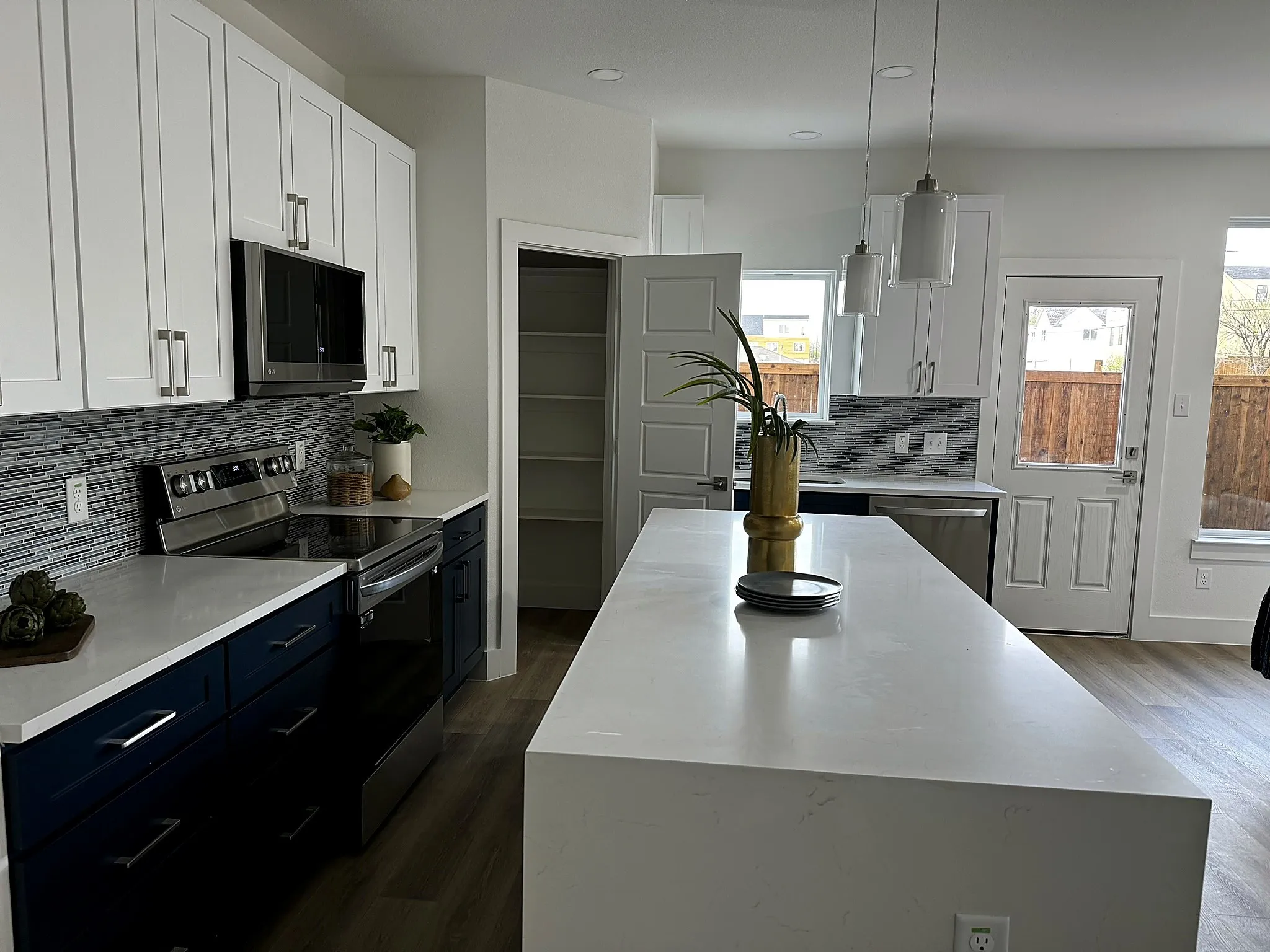 Modern kitchen featuring white upper cabinetry, navy lower cabinetry, and stainless steel appliances