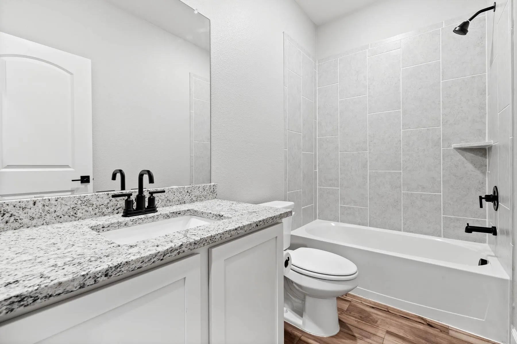 Bathroom with shower / bath combination, vanity, and wood finished floors