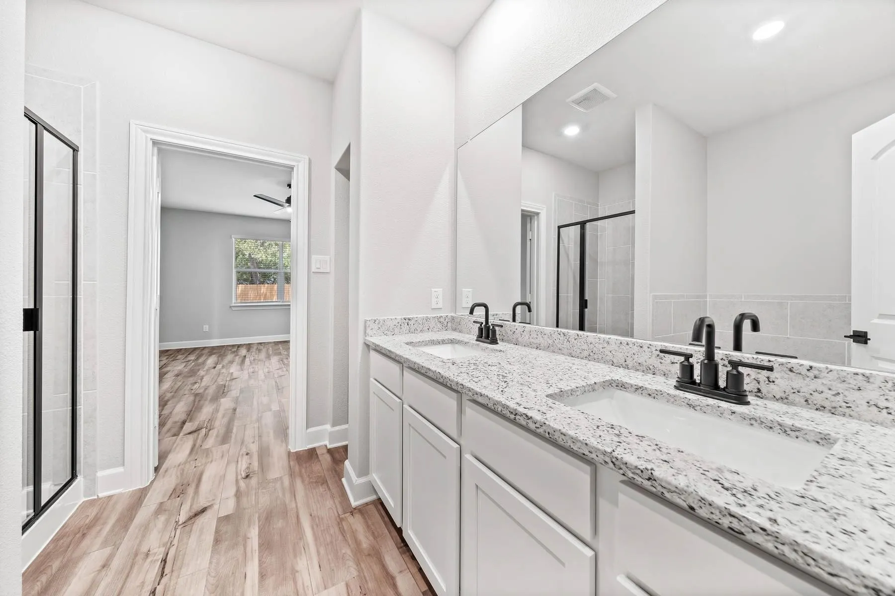 Full bathroom featuring double vanity, a stall shower, and light wood-type flooring