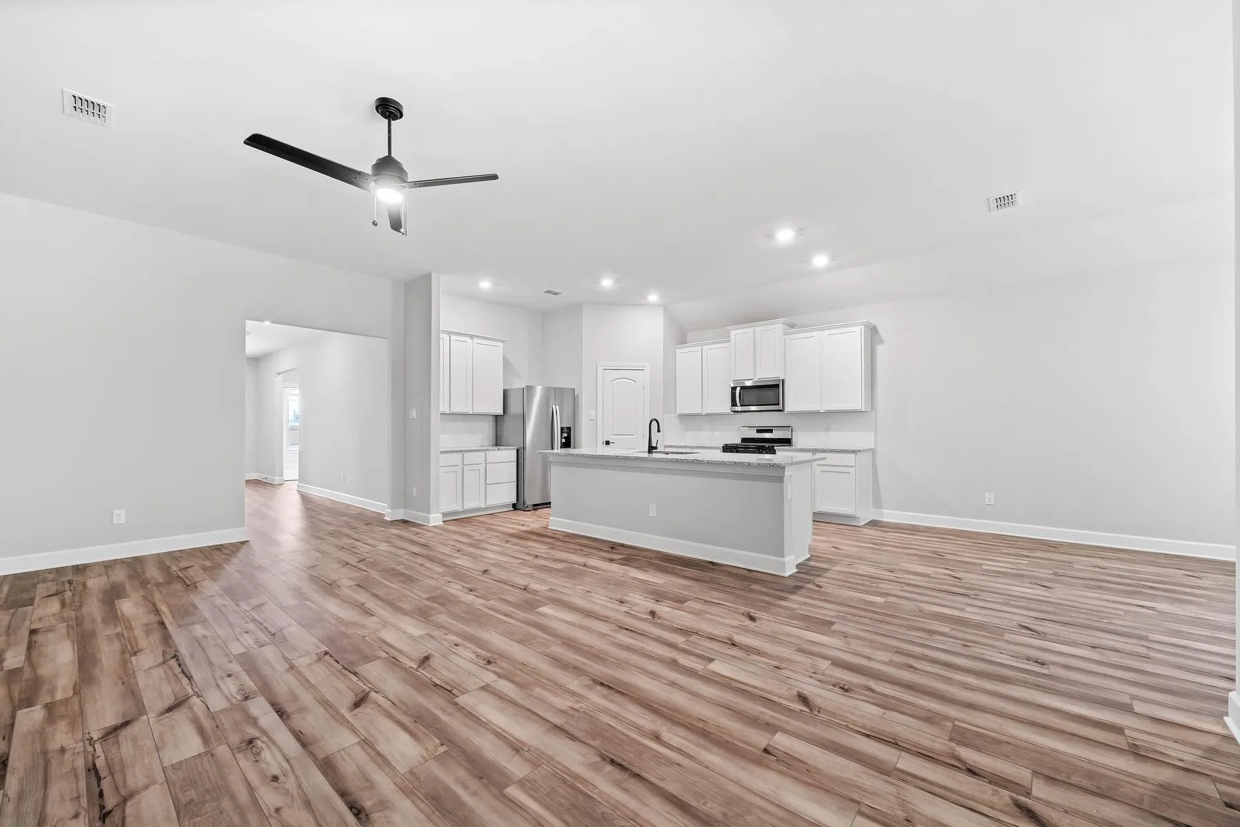 Kitchen with open floor plan, white cabinets, light wood finished floors, and recessed lighting