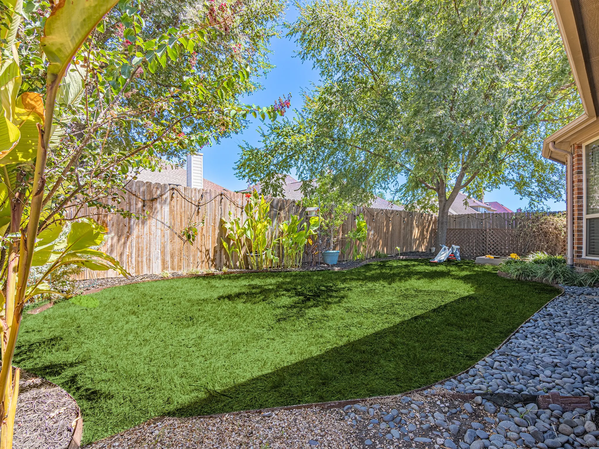 Expansive backyard featuring a manicured lawn, mature trees, and a privacy fence