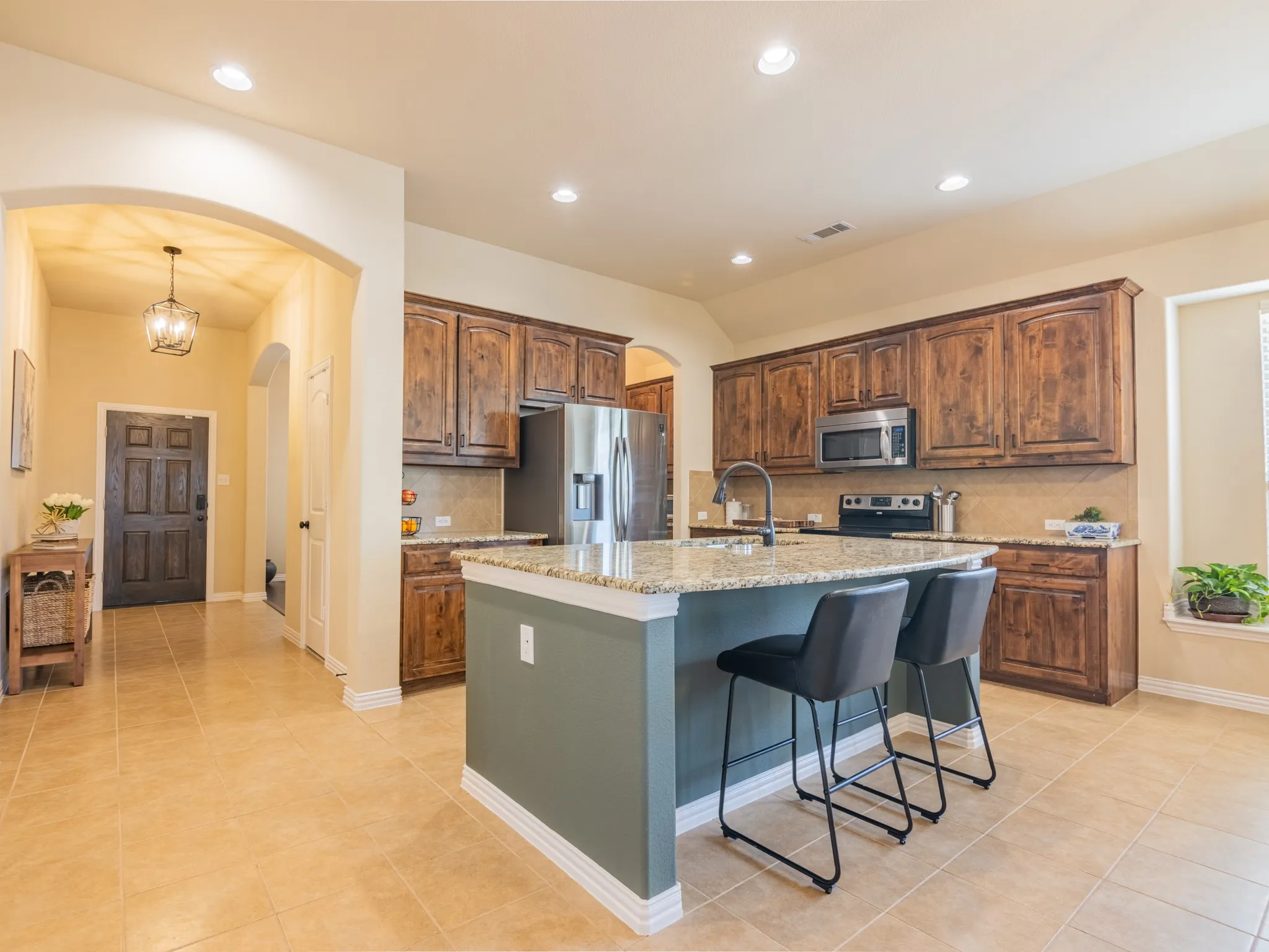 Kitchen featuring granite countertops, wood cabinetry, stainless steel appliances, and tile flooring
