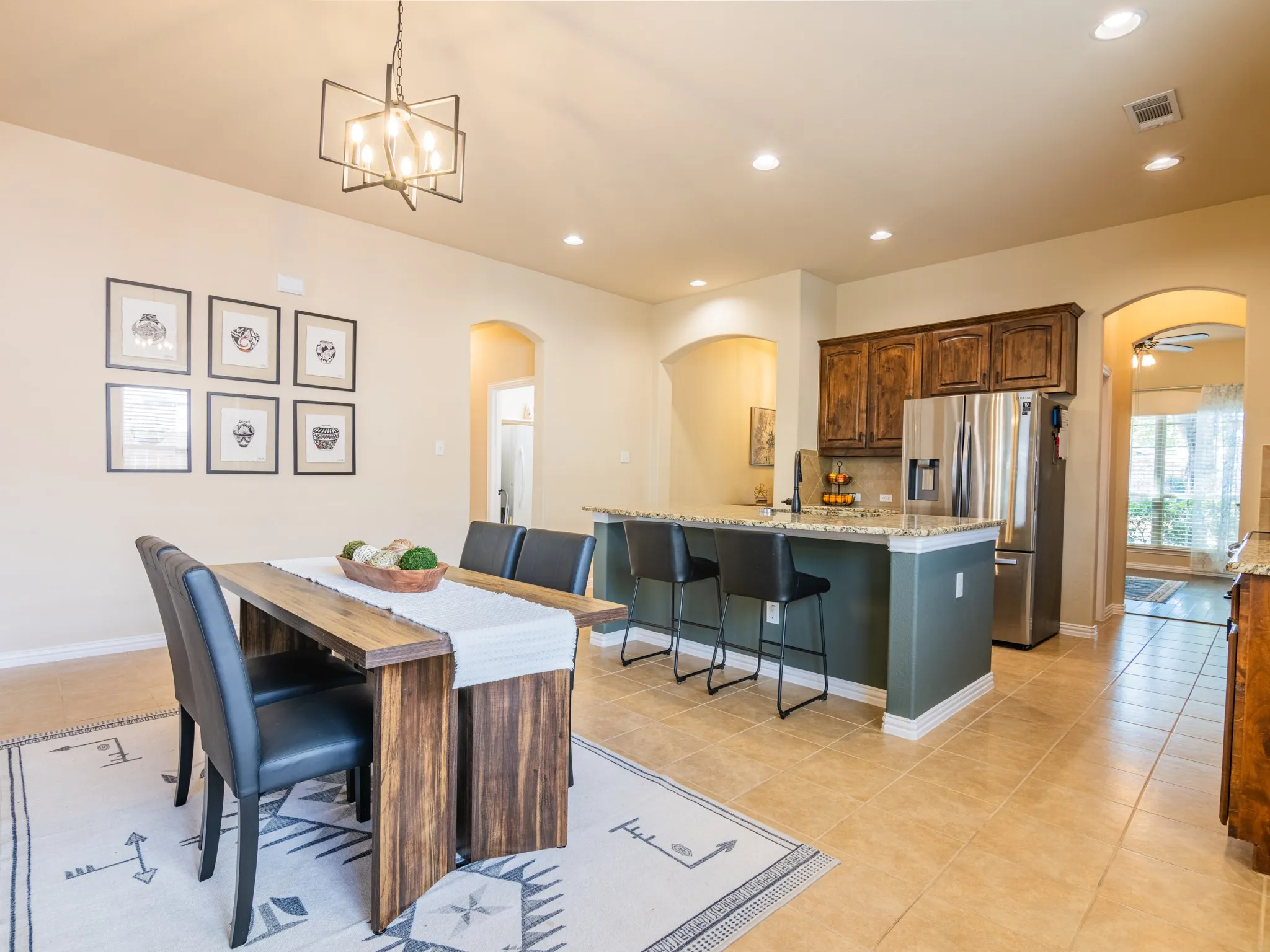 Kitchen and dining area featuring a breakfast bar with stone-finish countertop, wood-finish cabinetry, and tile flooring