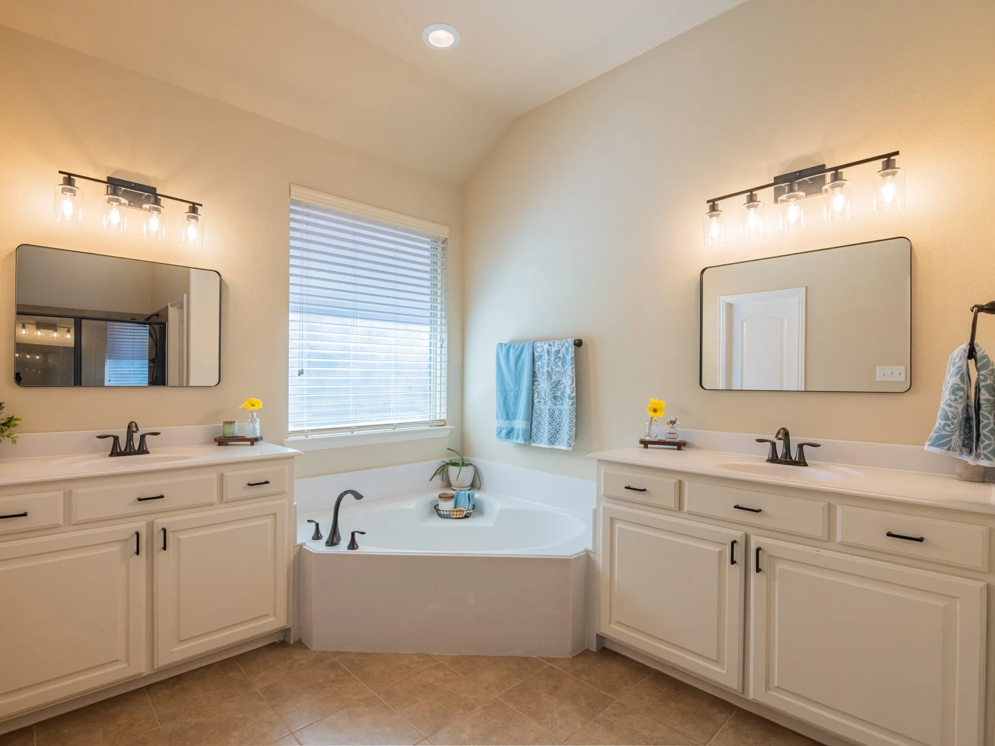Dual vanities with white countertops and undermount sinks, flanked by a built-in corner bathtub