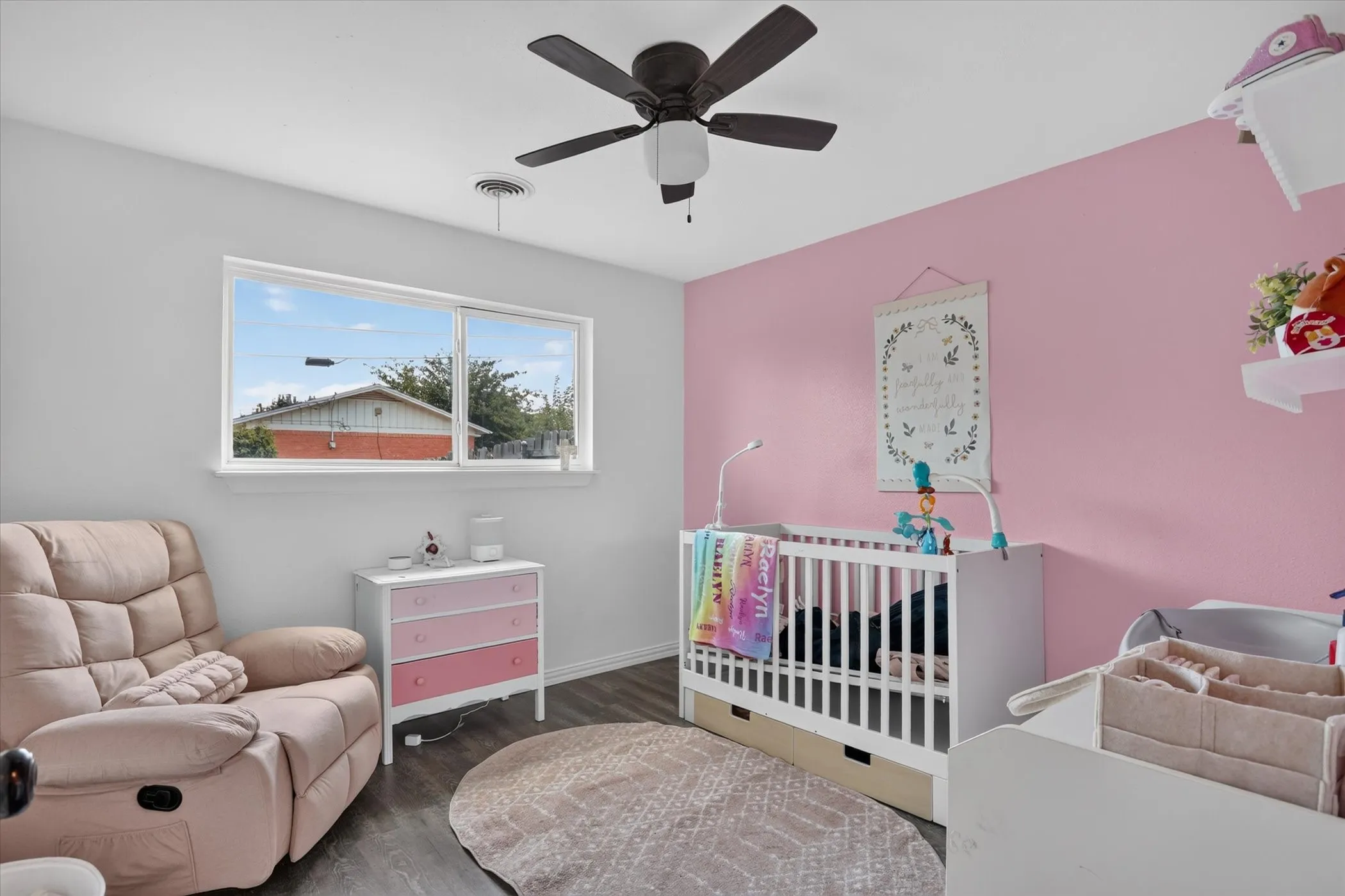White walls with an accent wall, wood-finish flooring, and a ceiling fan with integrated lighting