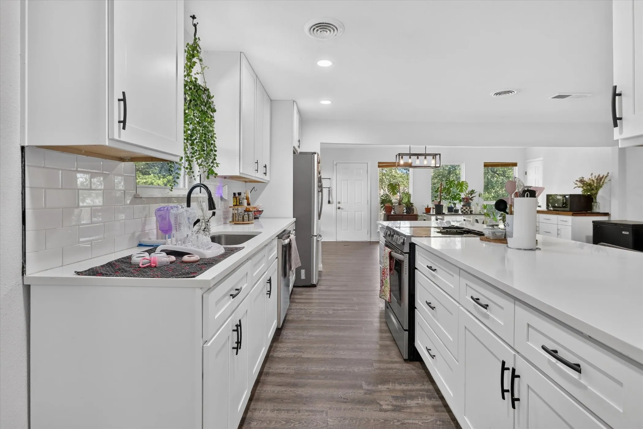 Spacious kitchen featuring white cabinetry, subway tile backsplash, a large center island, wood-finish flooring, and recessed lighting