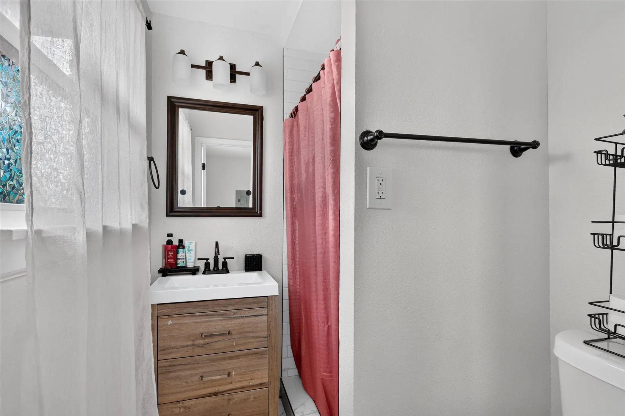 Wood-finish vanity with integrated sink, framed mirror, and wall-mounted light fixture