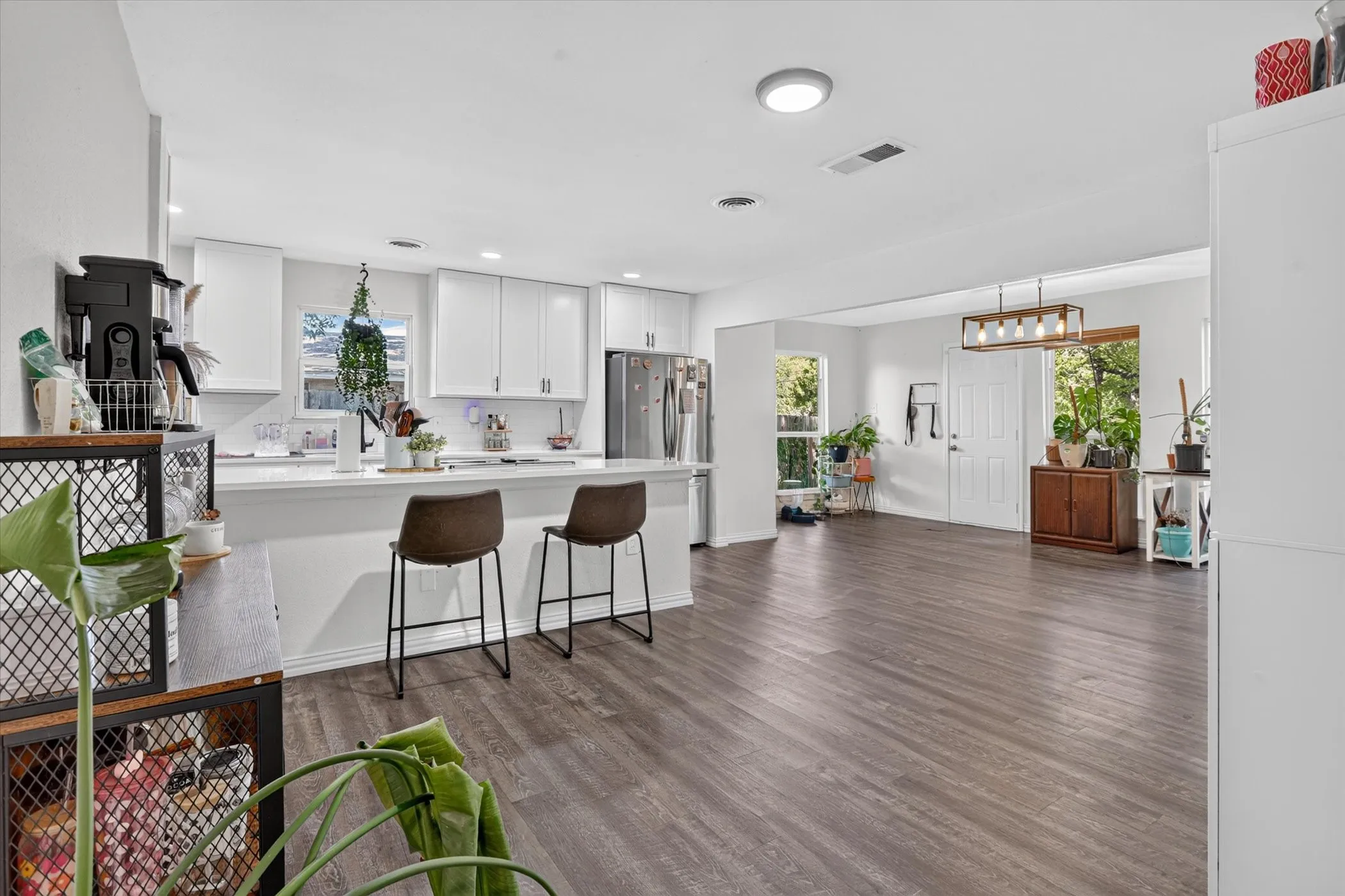 Open-concept living space with wood-finish flooring, white cabinetry, a kitchen island, and recessed lighting