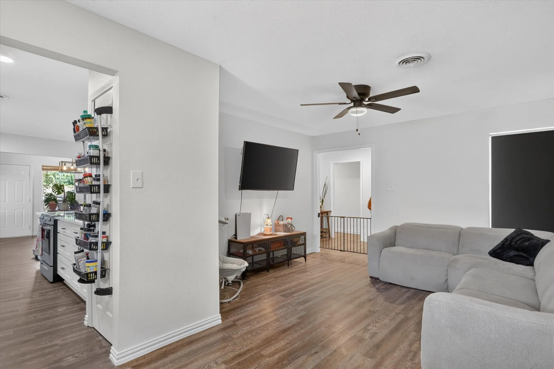 Hardwood-finish flooring throughout, ceiling fan with integrated lighting, built-in media console, and white painted walls