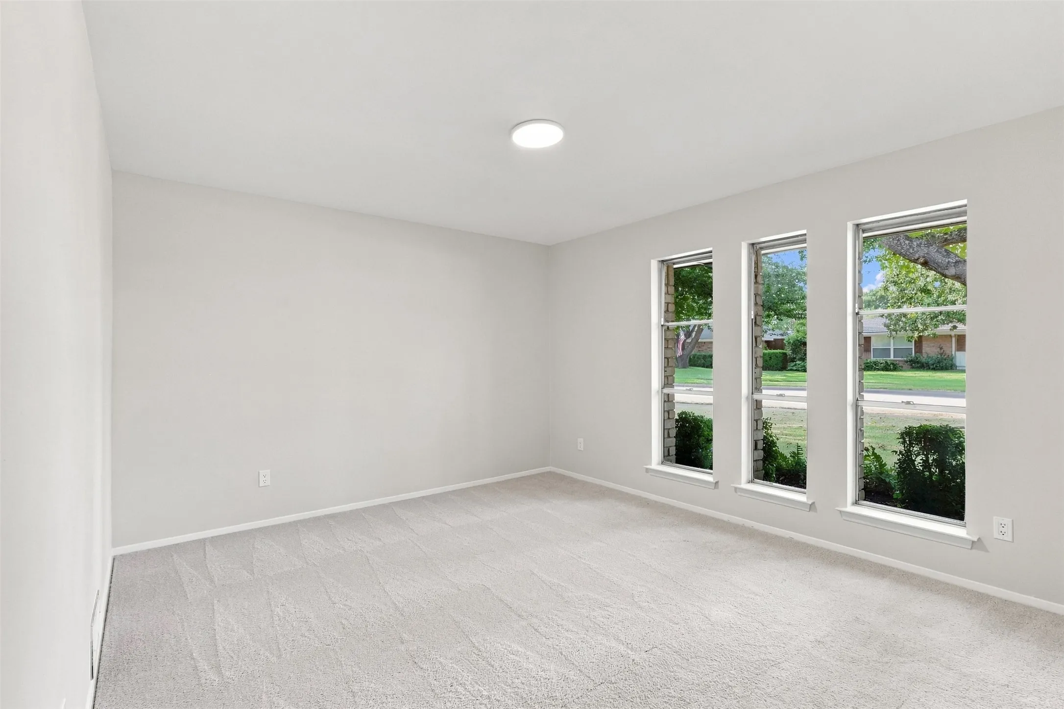 Neutral wall color, recessed ceiling light, and three vertical windows
