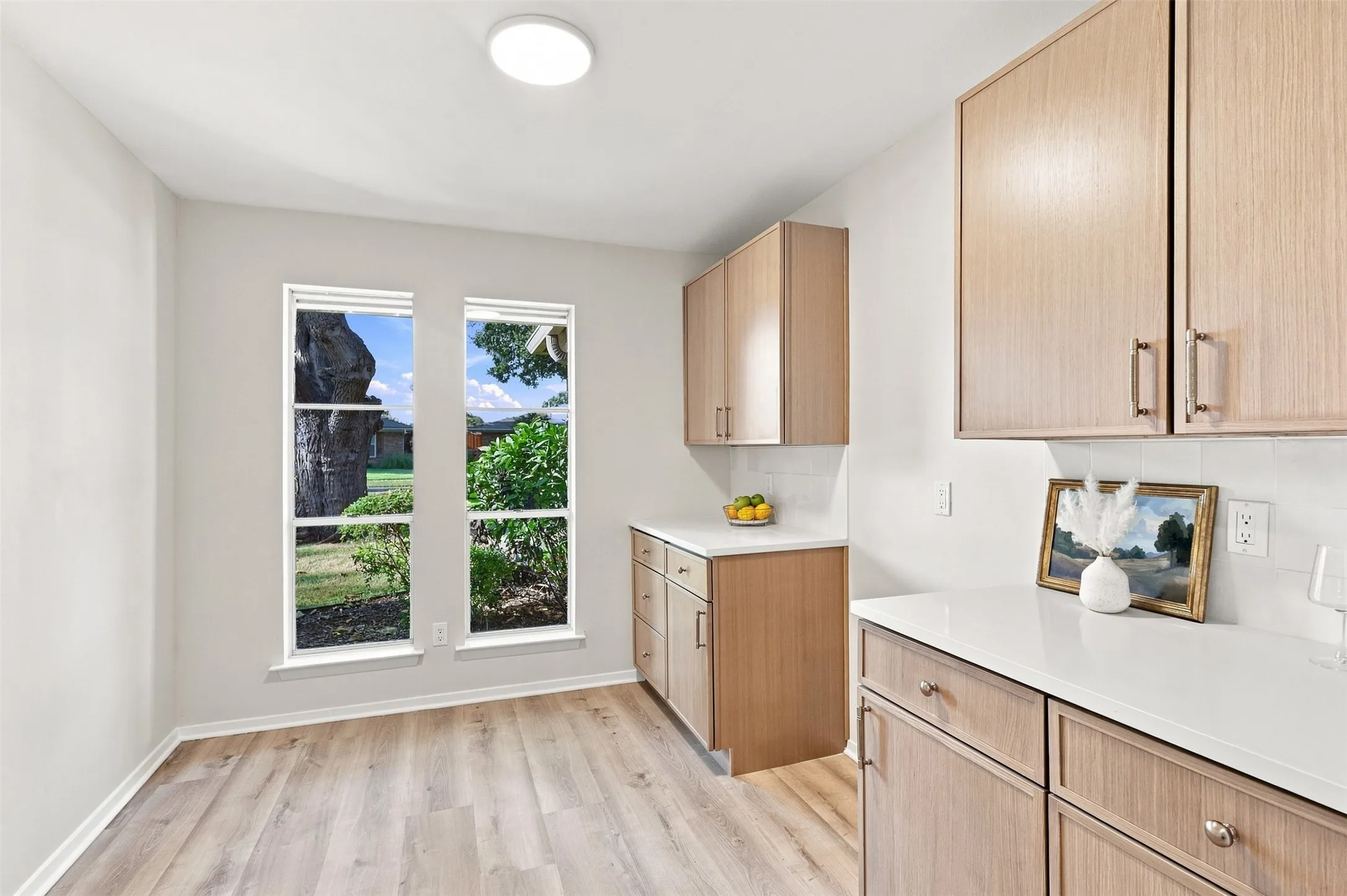 Wood-finish flooring with dual windows, recessed lighting, white countertops, and light wood cabinetry