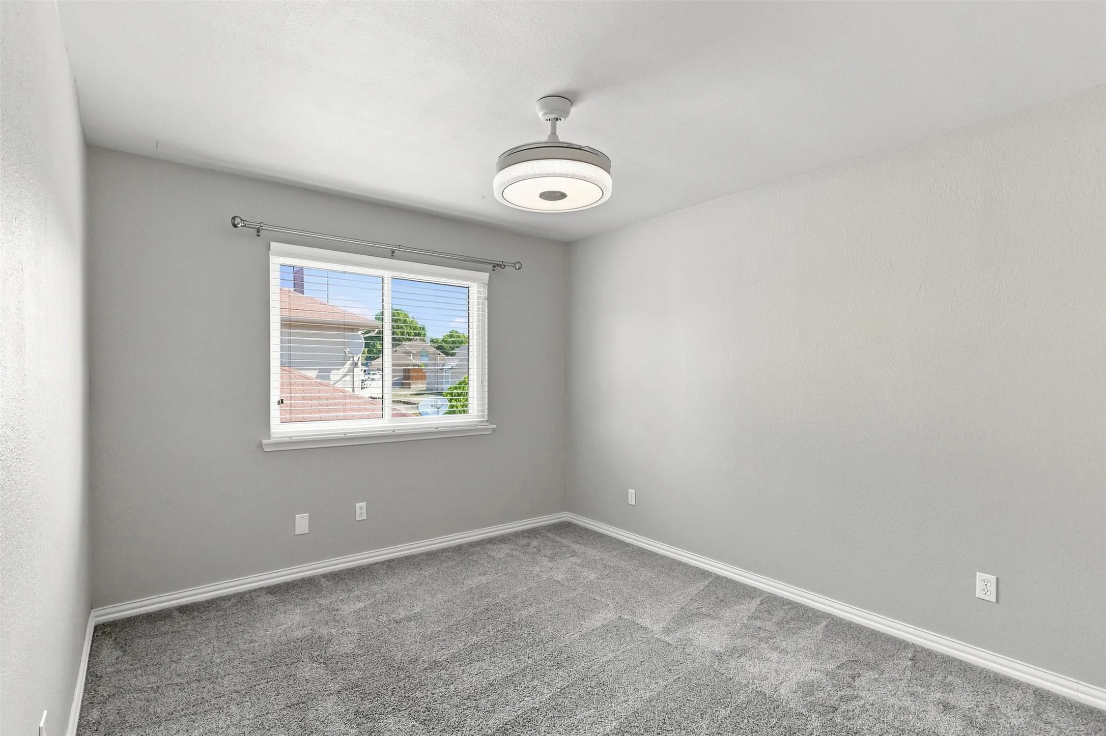 Secondary Bedroom with light carpet, decorative lighting and window looking to the side of the home.