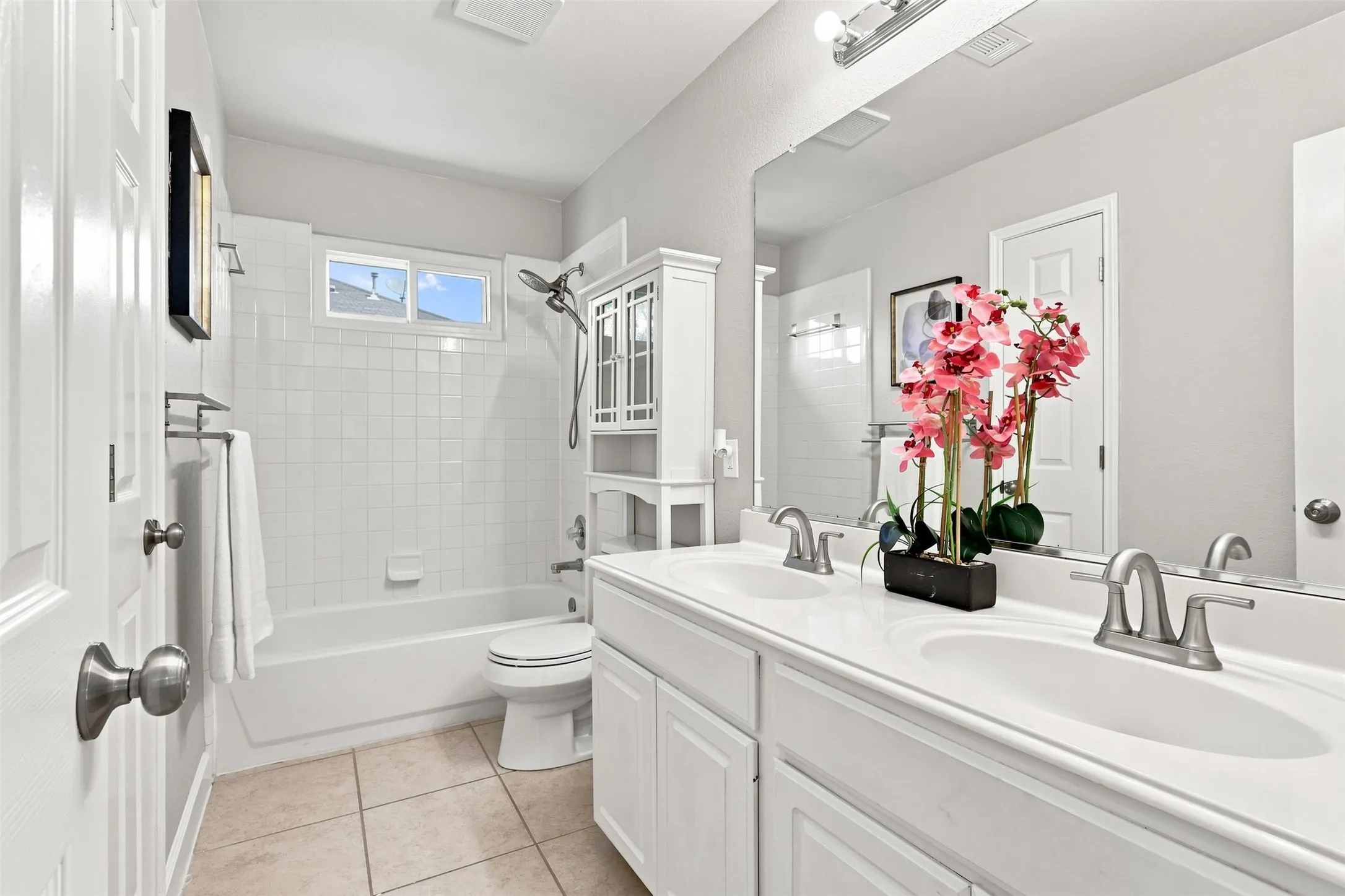 Full bathroom upstairs features dual sinks, shower/tub combo and tile flooring.