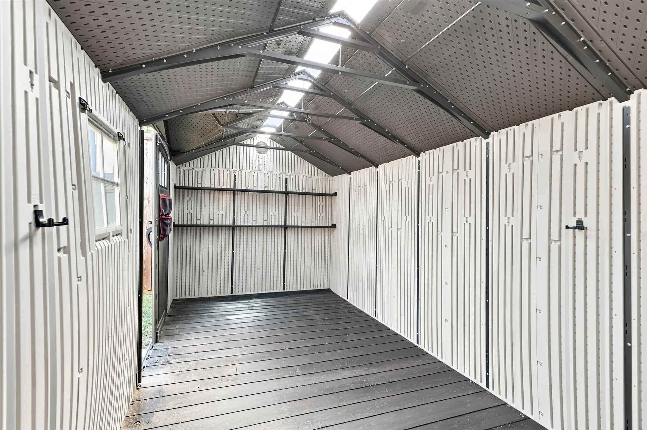 Spacious storage shed featuring a pitched roof, integrated skylights, a dedicated window, and durable flooring.