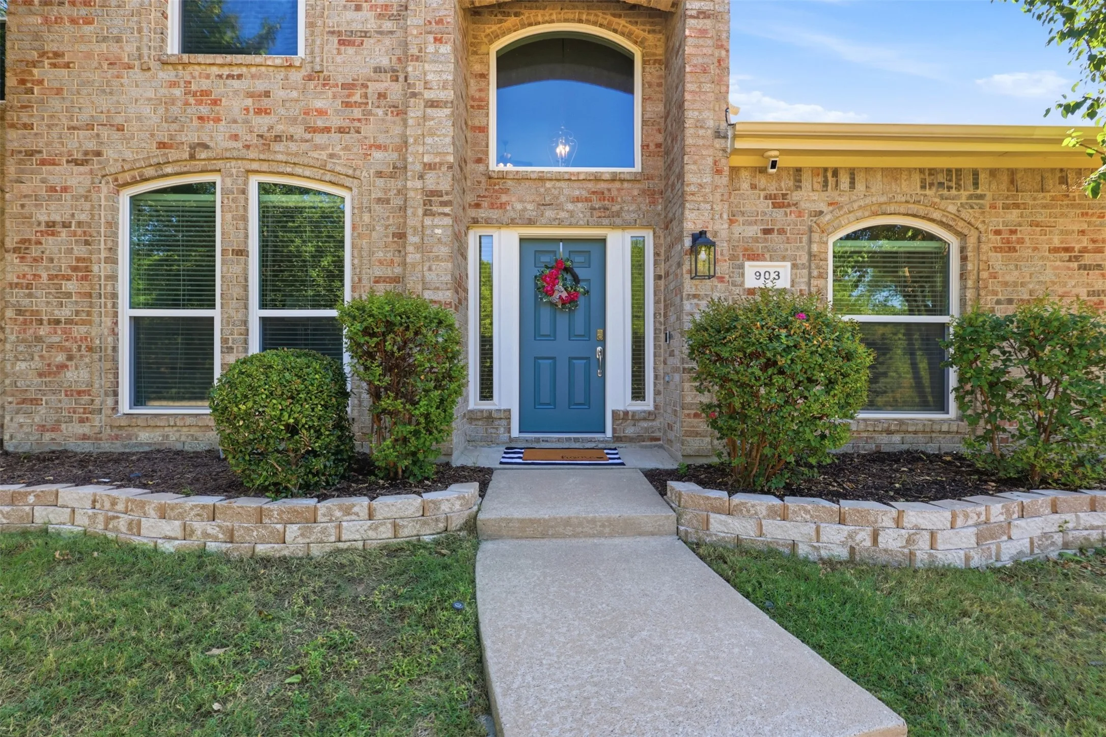 Landscaping beds and striking blue front door create instant curb appeal.