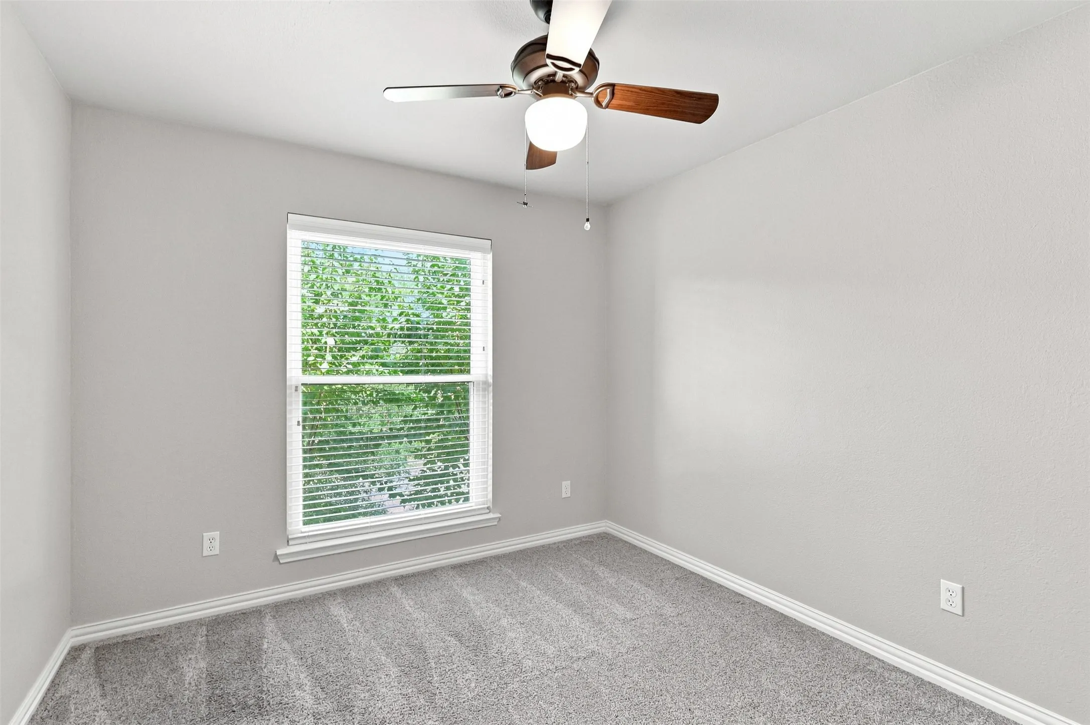 Third bedroom with large window, ceiling fan and light carpet.