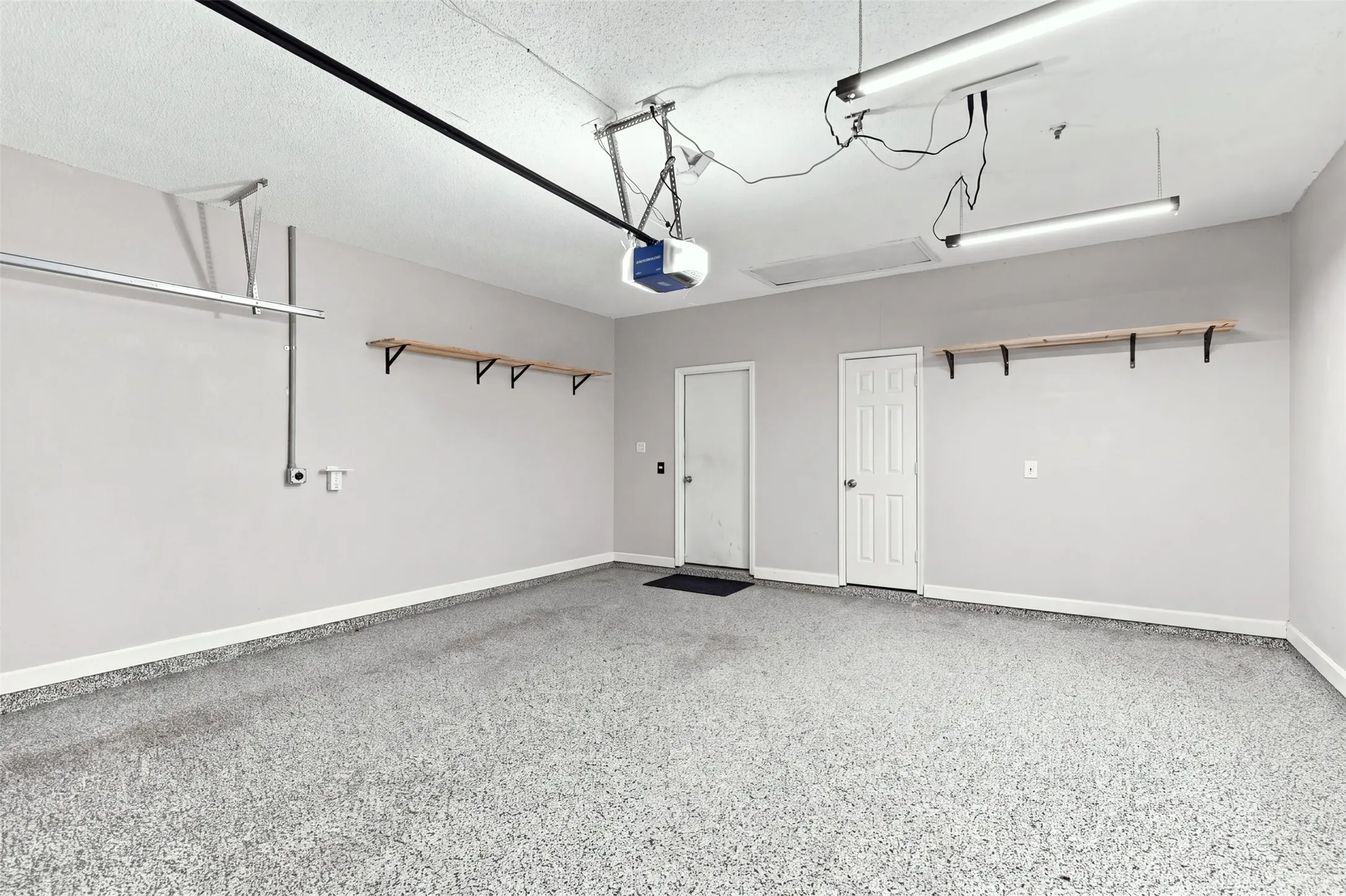 Garage with epoxy flooring, neutral wall tones, and wall-mounted shelving.