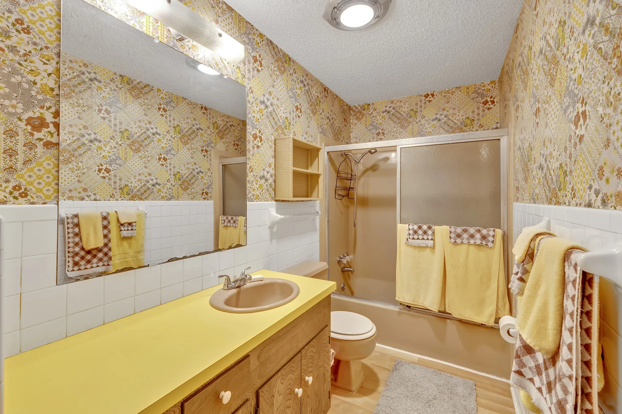 Bathroom featuring a vanity with a yellow countertop, a single basin sink, and a wood-finish cabinet