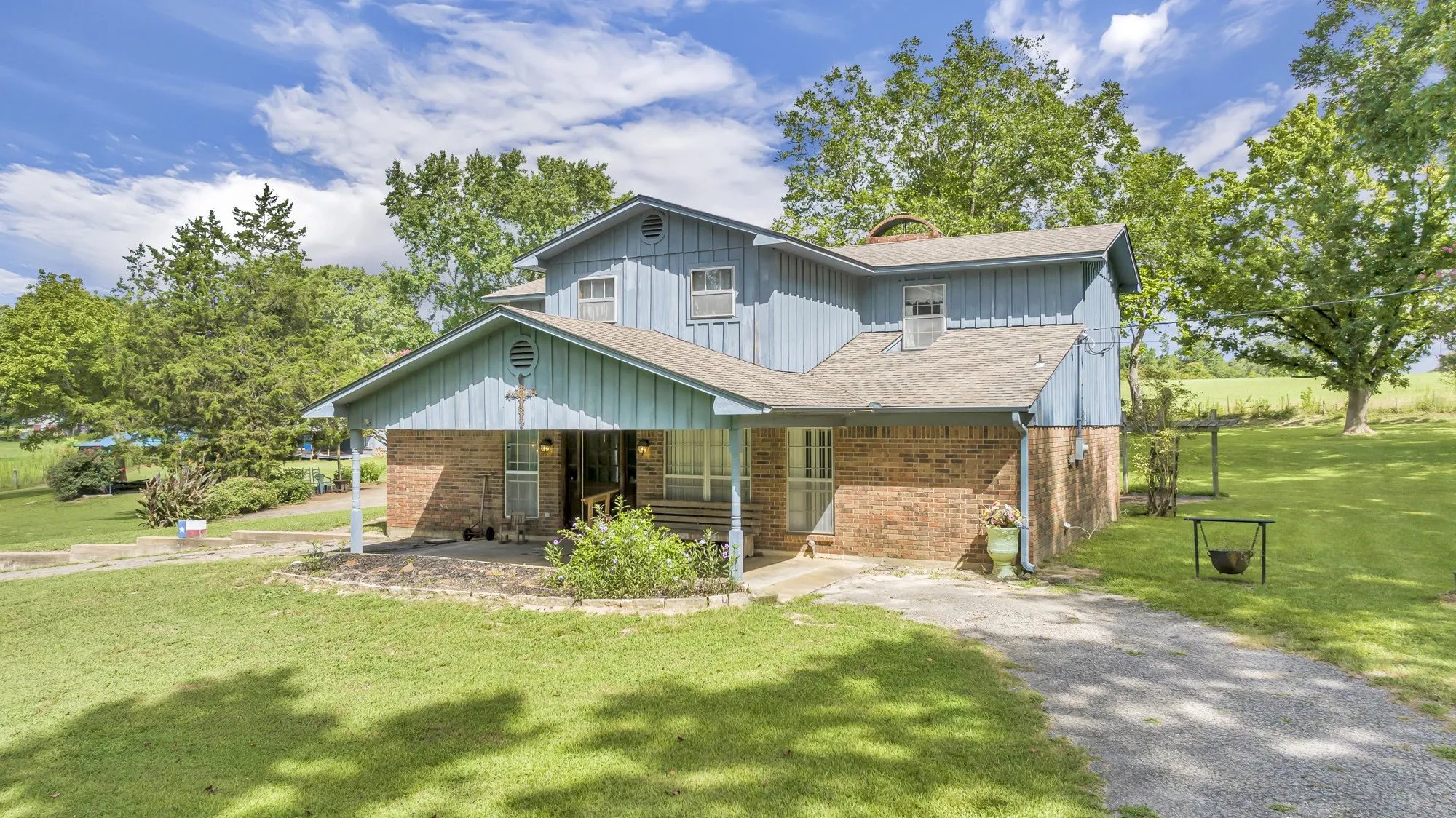 Two-story residence featuring brick and siding exterior, front porch, and a gravel driveway