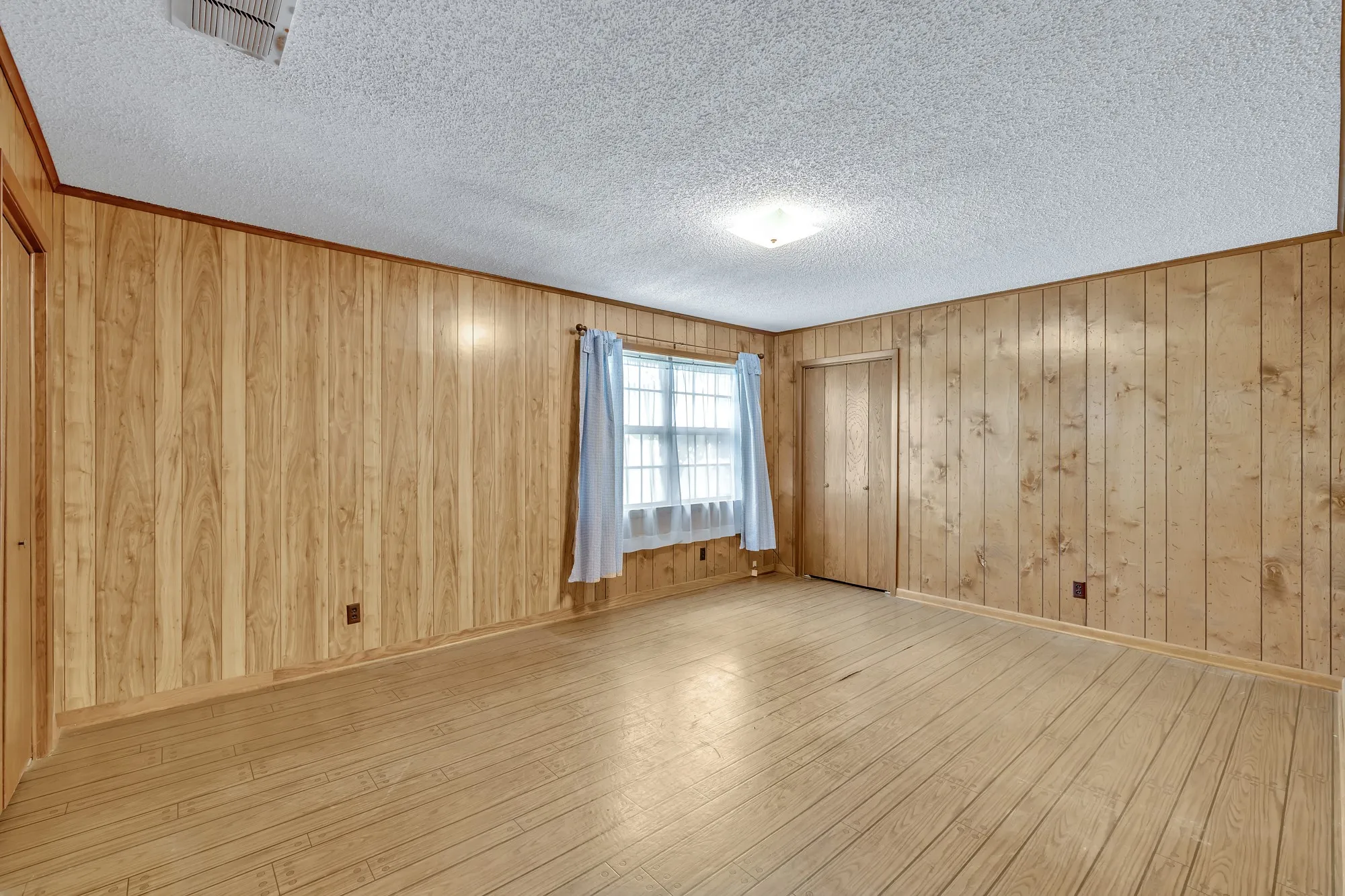 Wood paneling throughout, wood-finish flooring, and a flush mount ceiling light