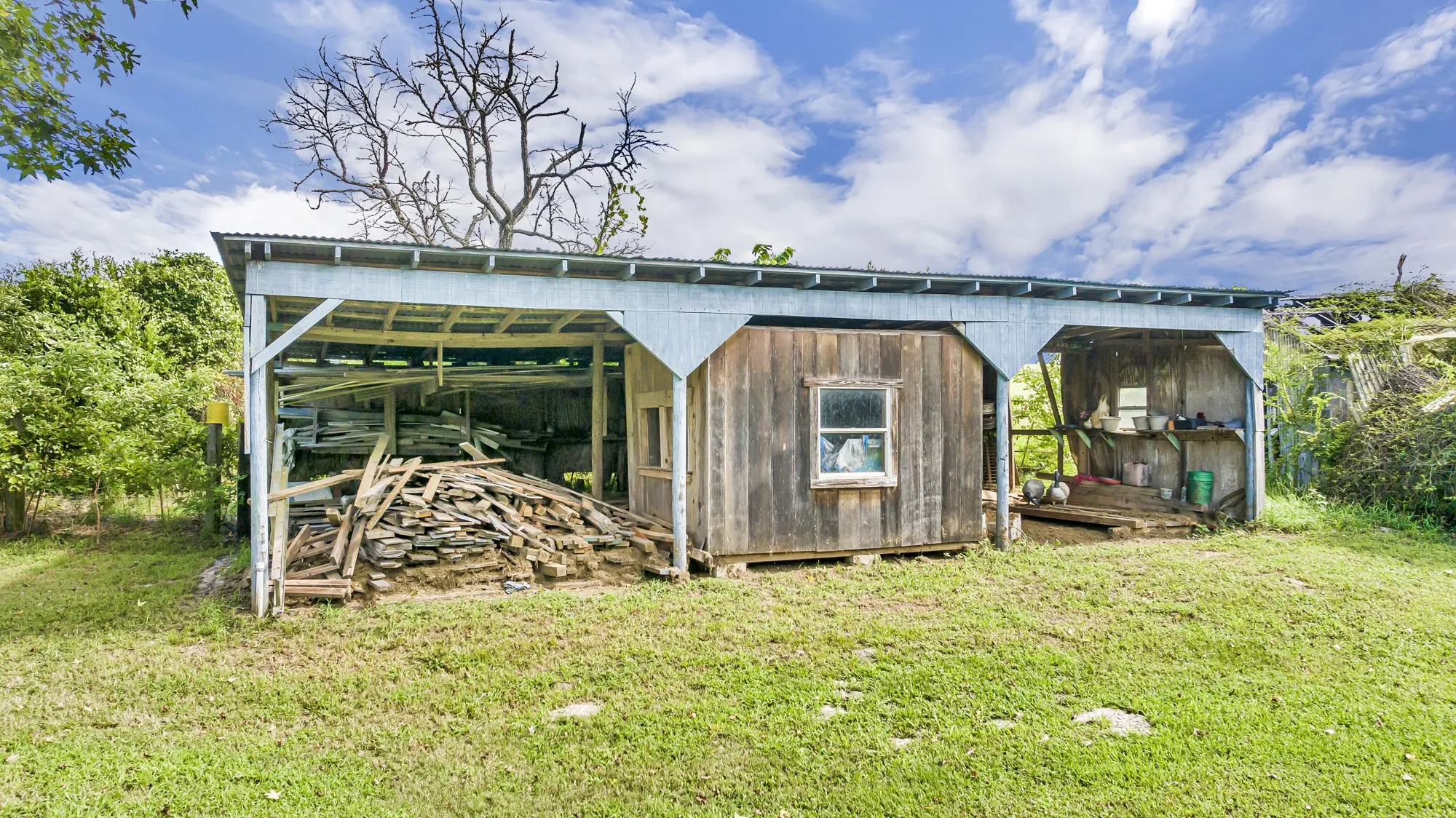 Outdoor shed structure with corrugated metal roofing, exposed wood framing, and wood plank siding