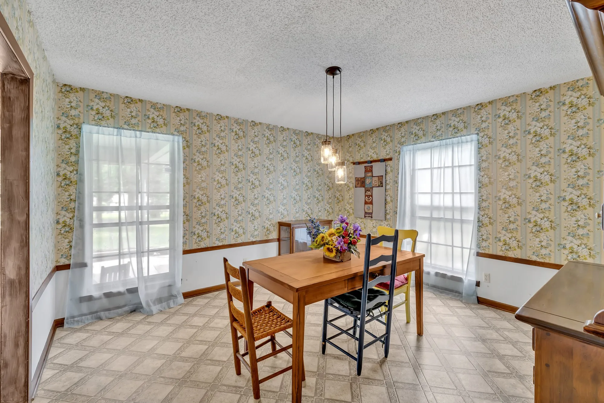 Patterned wallpaper with a decorative chair rail, multiple windows, and a built-in display cabinet
