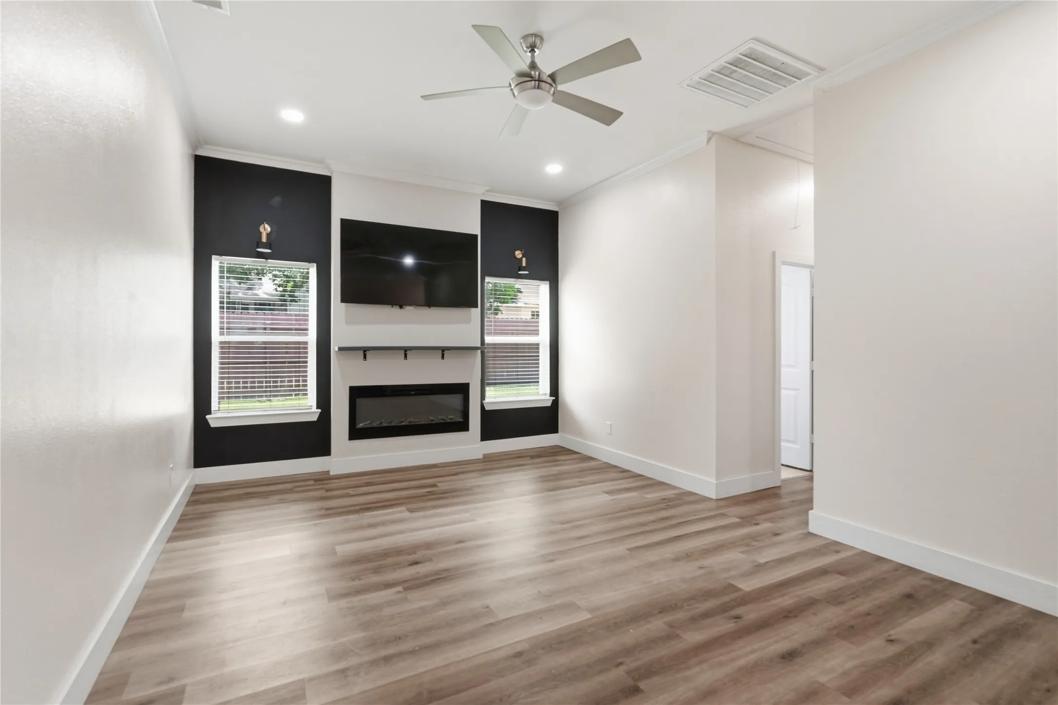 Spacious interior with wood-finish flooring, an integrated electric fireplace, and a ceiling fan