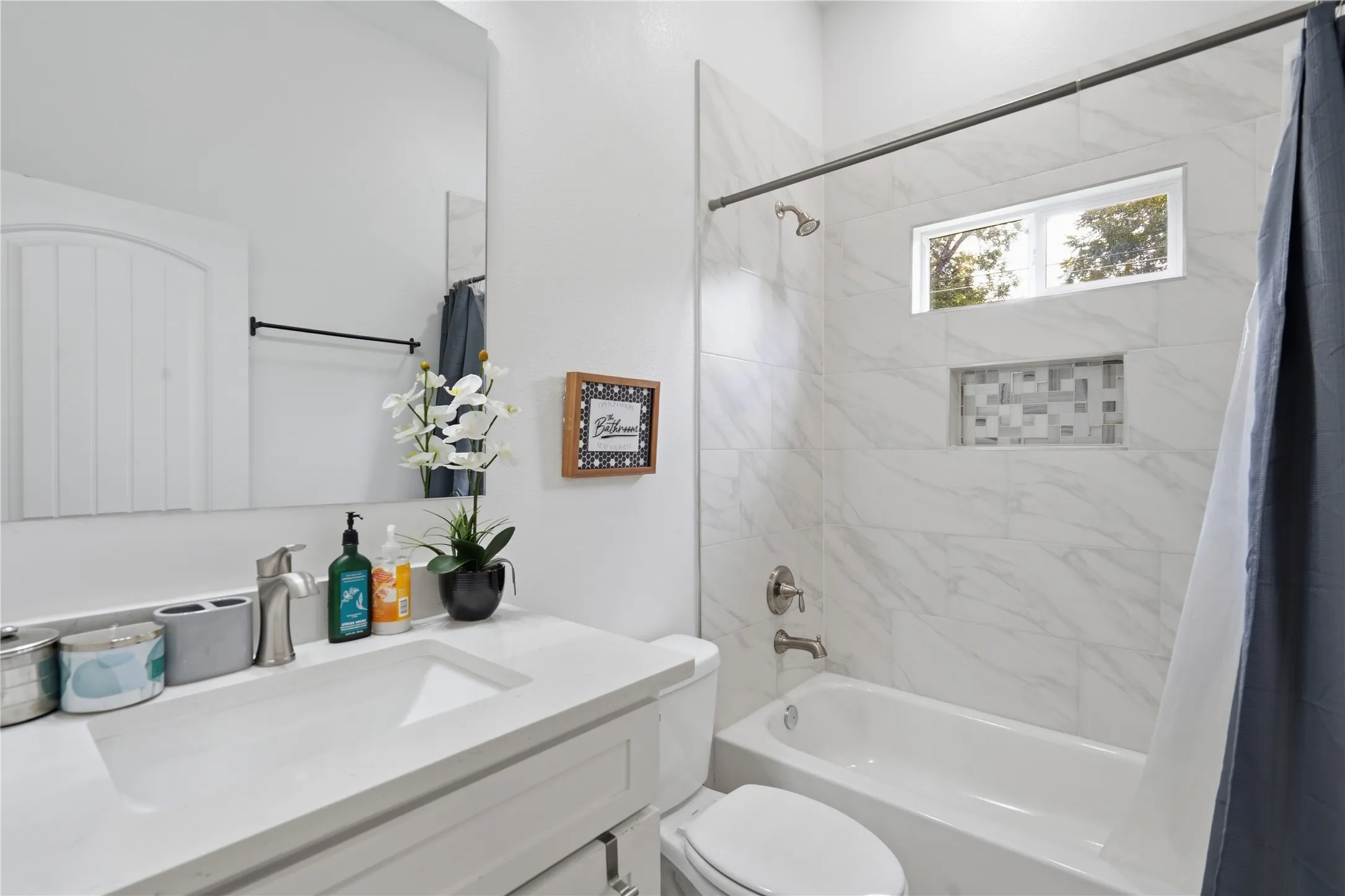 Bathroom featuring a single vanity with an integrated sink and brushed nickel faucet