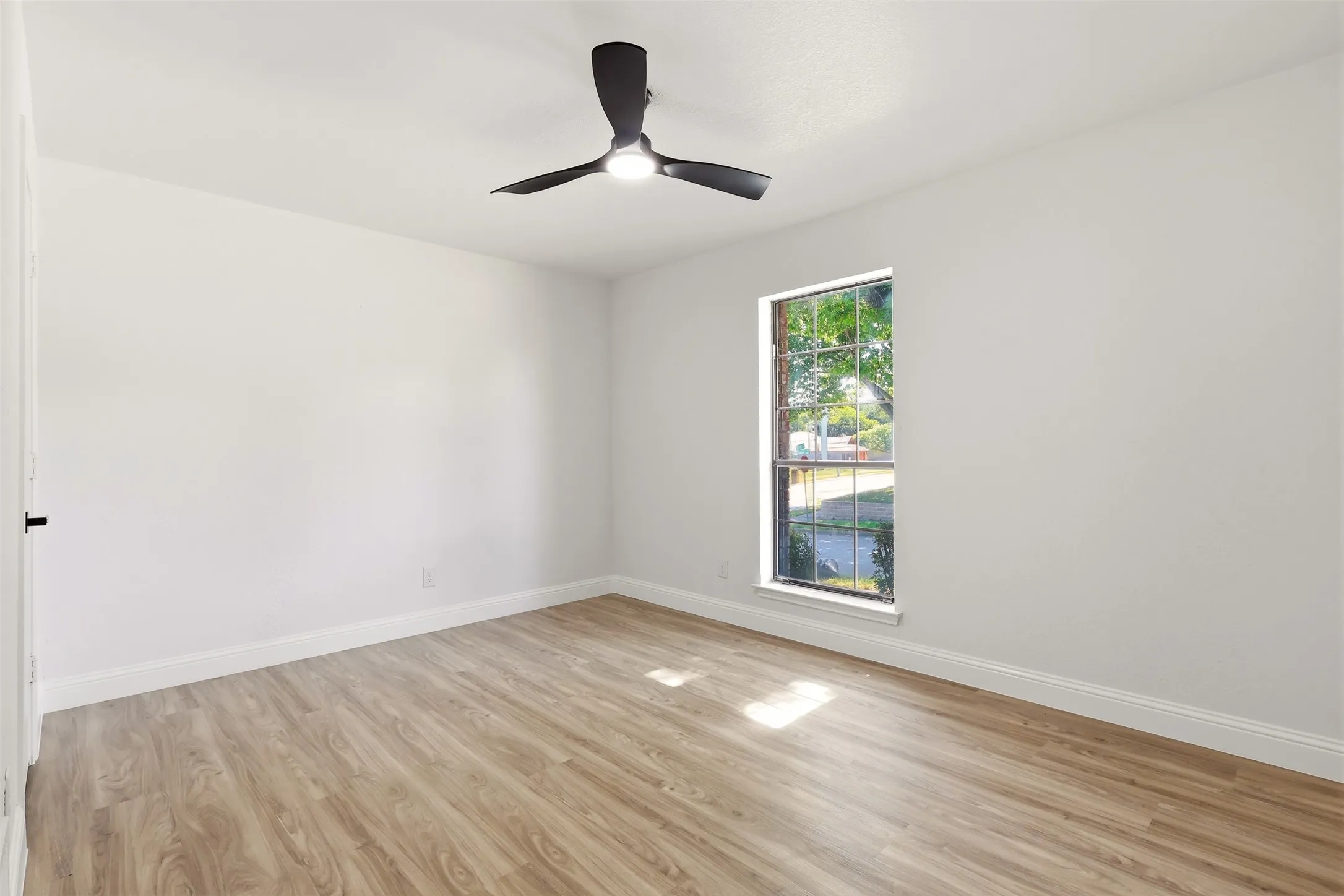 Crisp white walls, wood-finish flooring, and a modern ceiling fan with integrated lighting