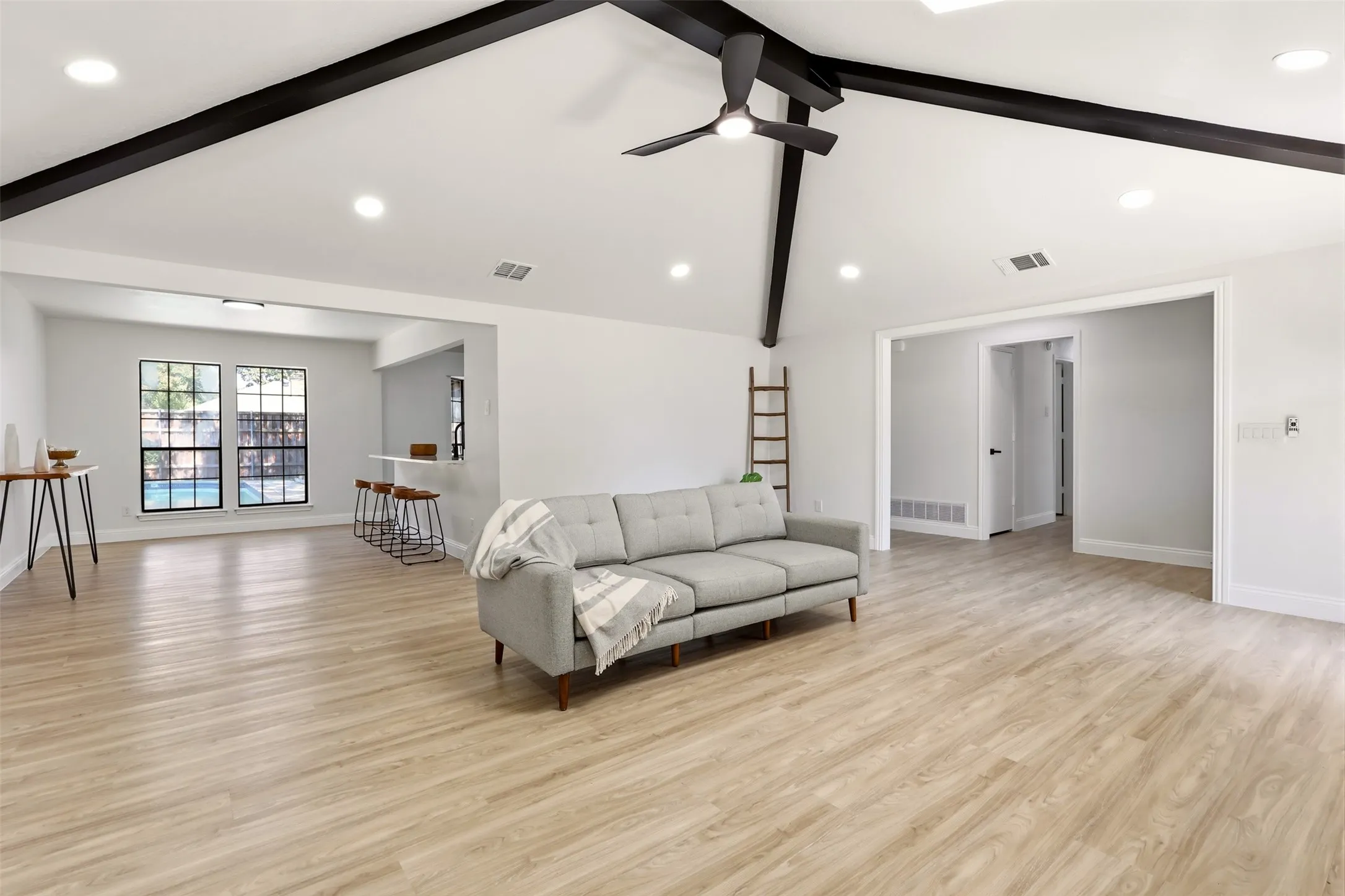 Vaulted ceilings with exposed beams, wood-finish flooring, recessed lighting, and a ceiling fan