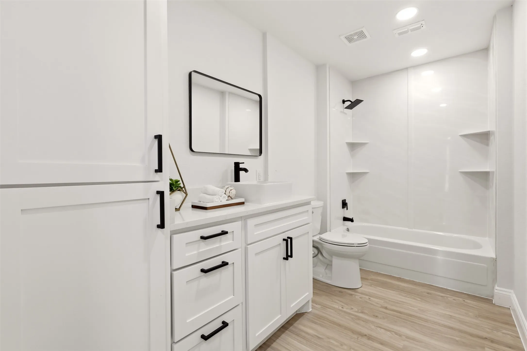Modern bathroom featuring a white vanity with multiple storage drawers, quartz countertop, and matte black hardware