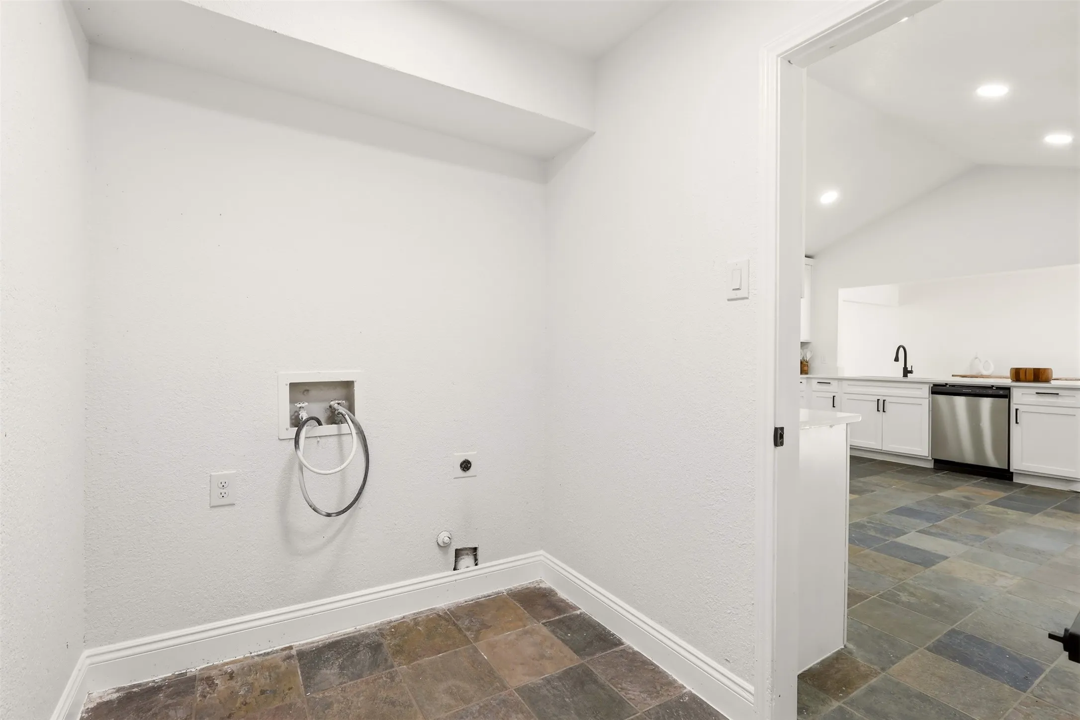 Dedicated laundry room featuring slate-finish tile flooring, white shaker cabinetry, stainless steel appliances, recessed lighting, and chrome towel ring fixture