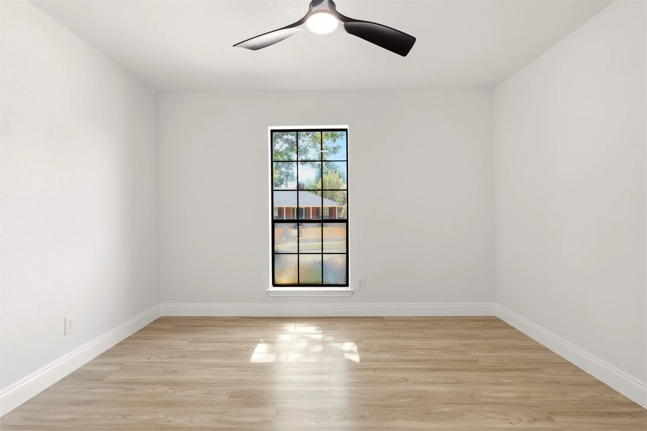Bright, open room showcasing pristine wood-finish flooring and clean white walls