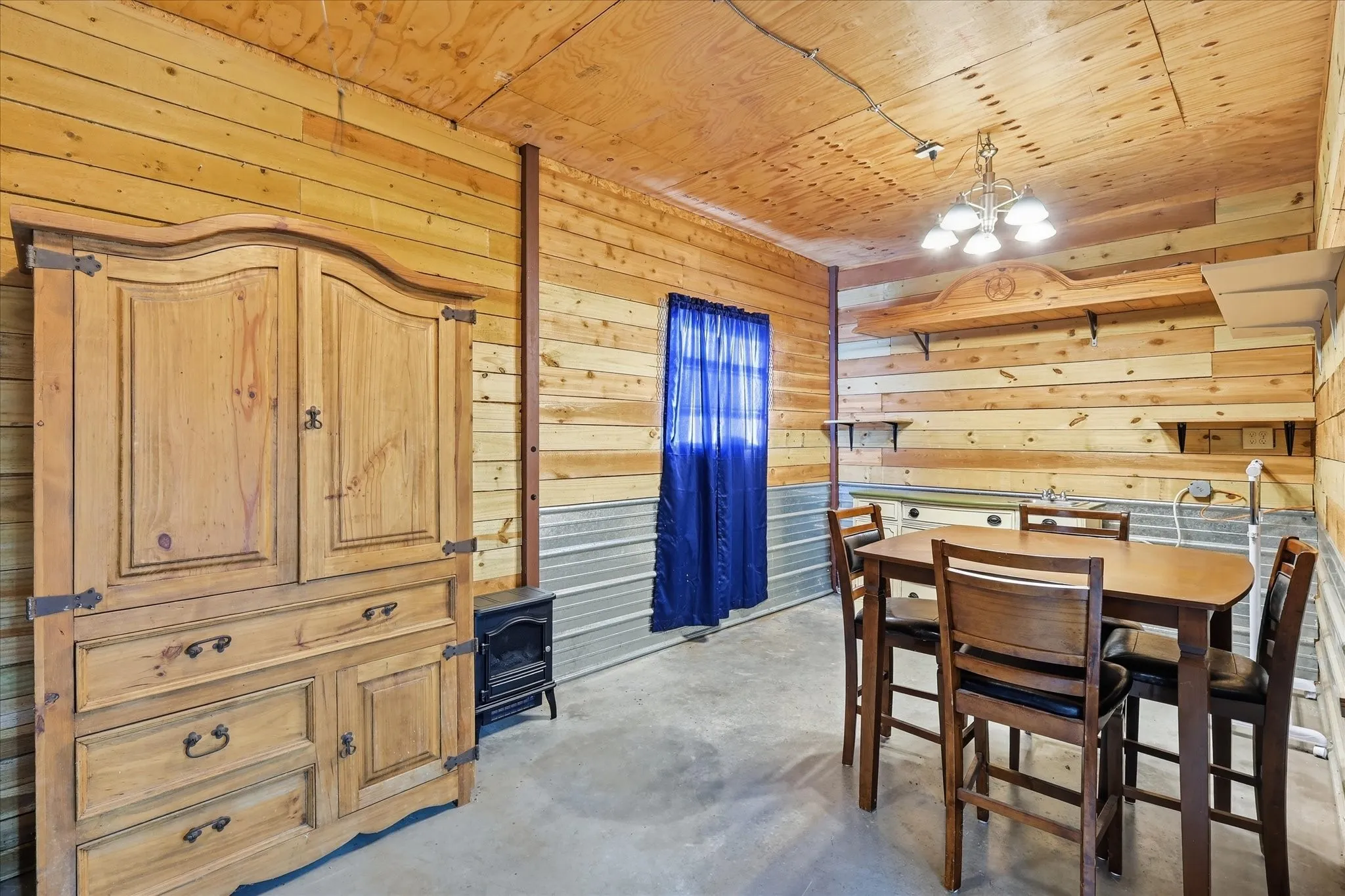 Wood paneling on walls and ceiling, metal wainscoting, and concrete flooring