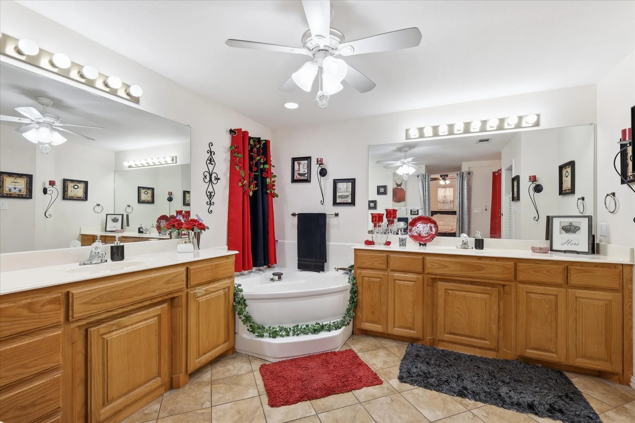 Dual wood-finish vanities with light countertops, expansive wall-mounted mirrors, and an angular soaking tub