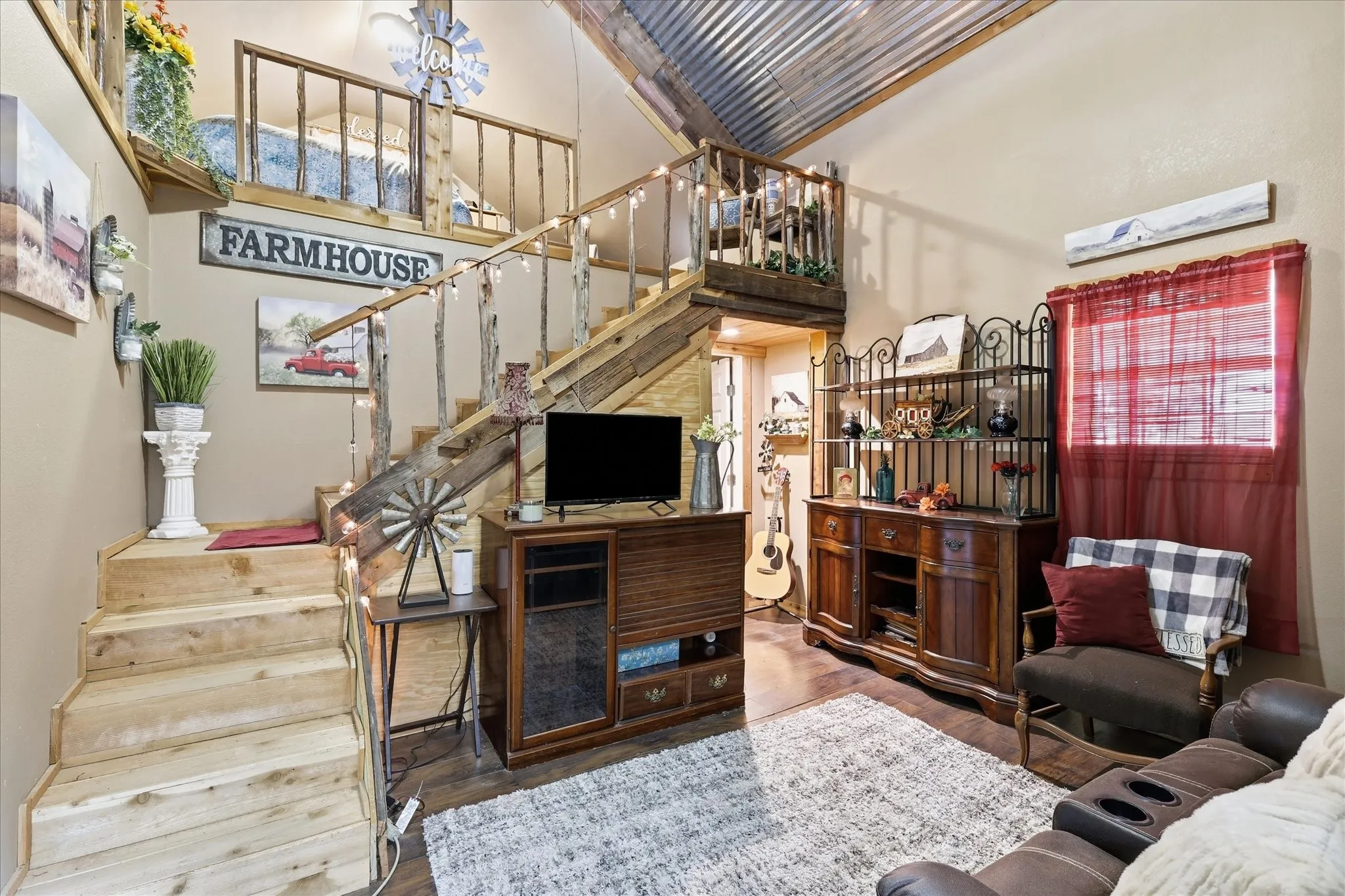 Vaulted ceiling with corrugated metal finish, wood-finish flooring, and natural wood staircase leading to a loft